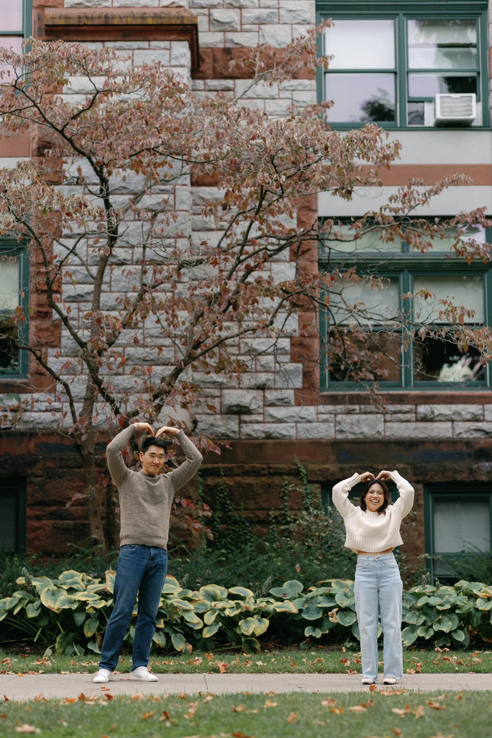 A couple making hearts with their arms together and laughing 