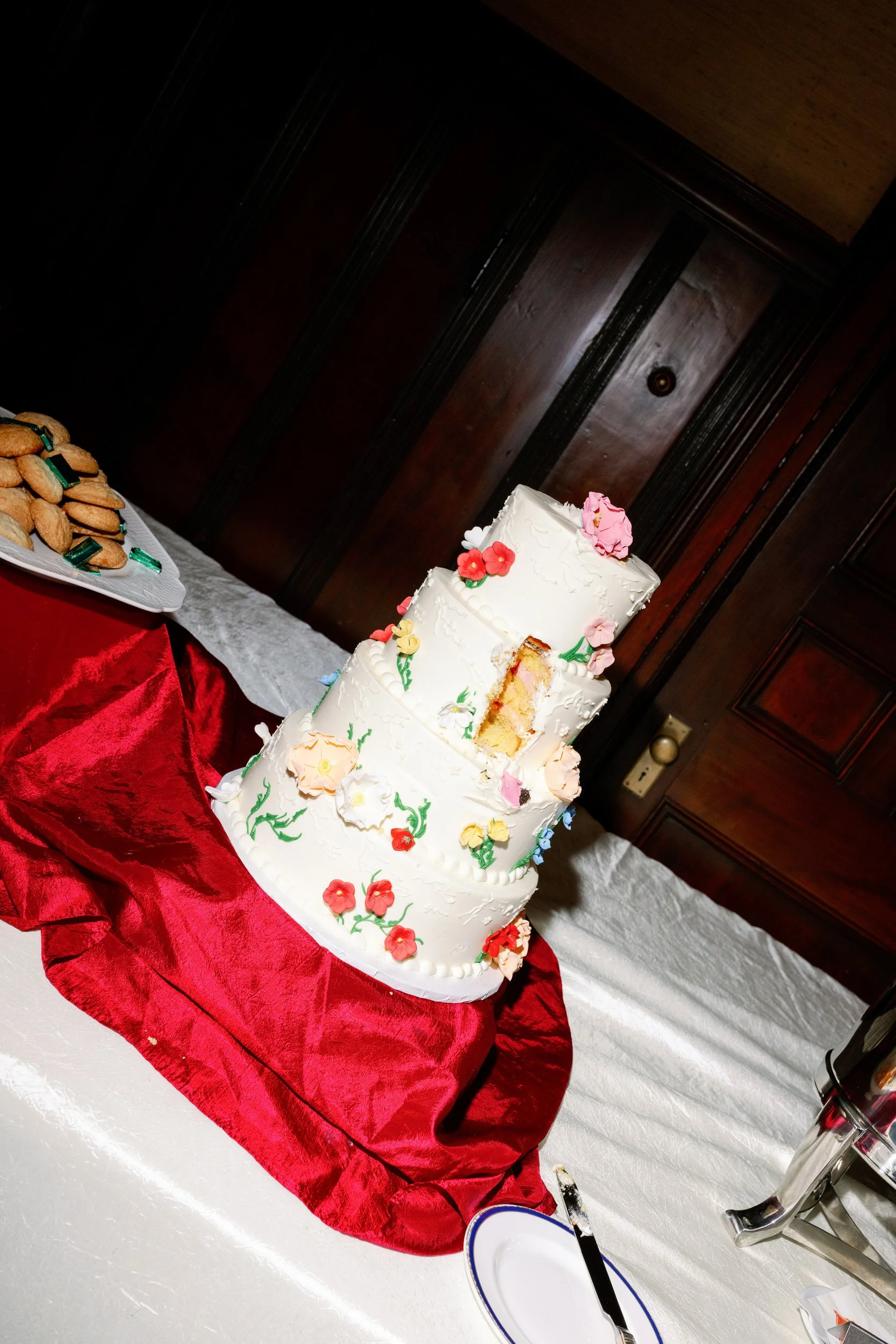 A four tiered wedding cake with a slice cut out 