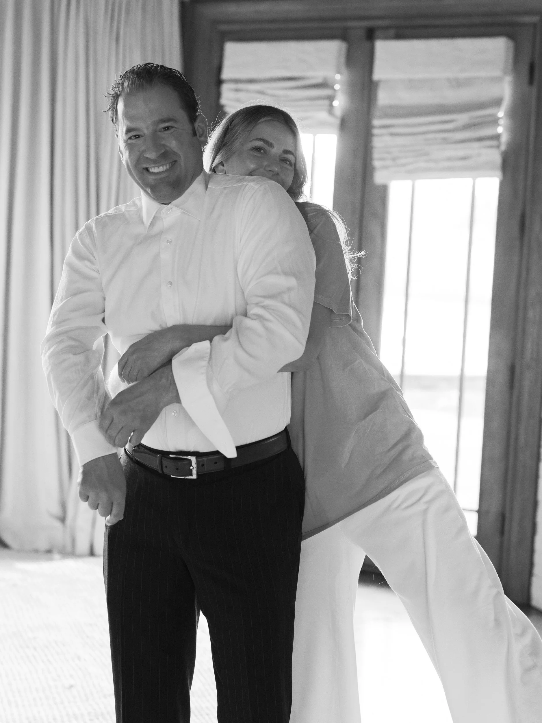 A person hugging their partner from behind as they both smile