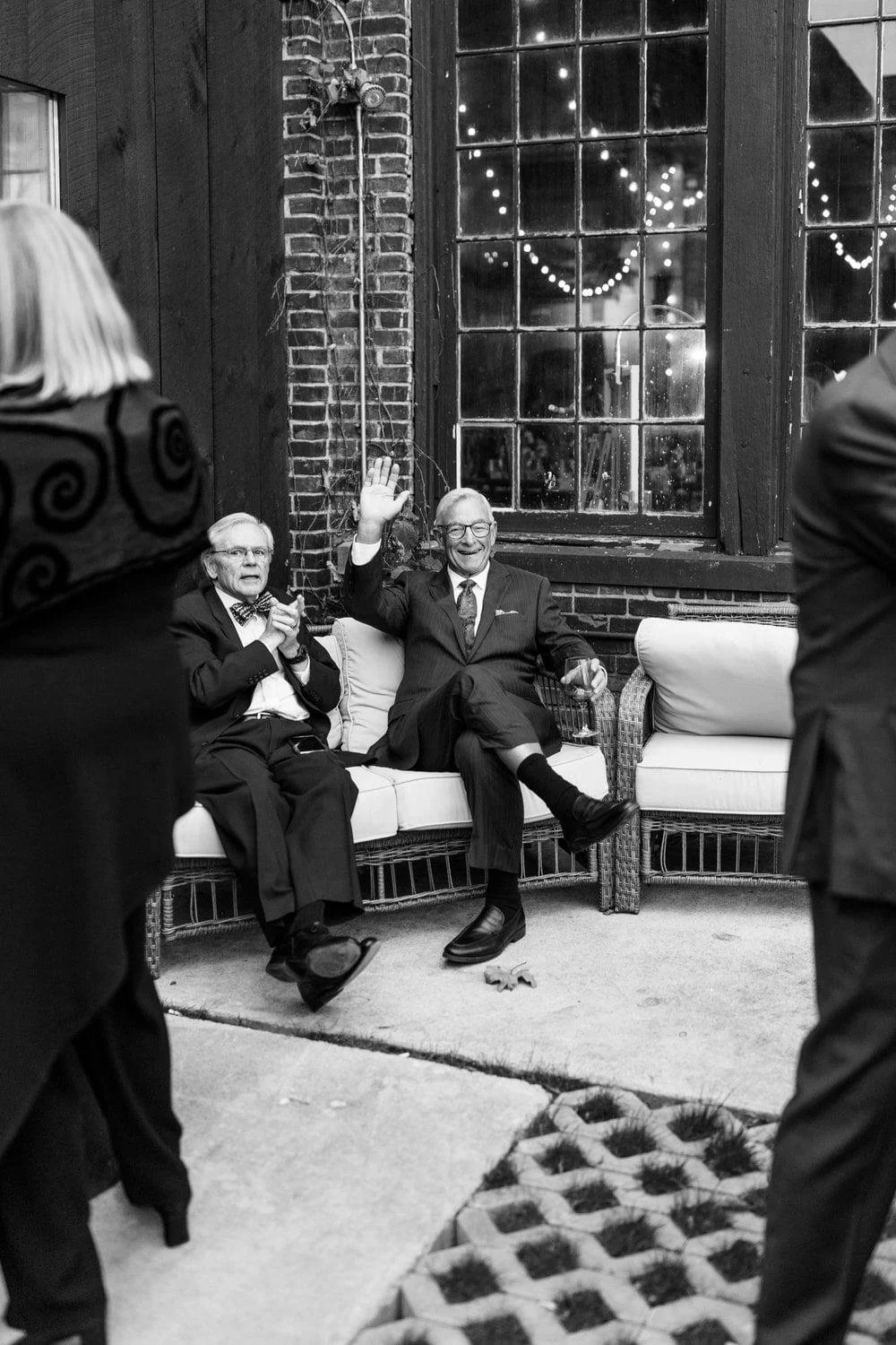  Two people in suits sitting down on an outdoor couch 