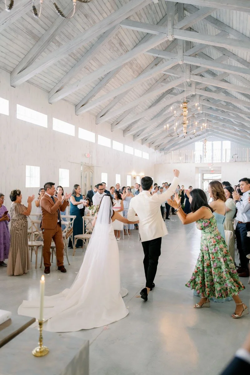 Newlyweds walking back up the aisle as their guests cheer