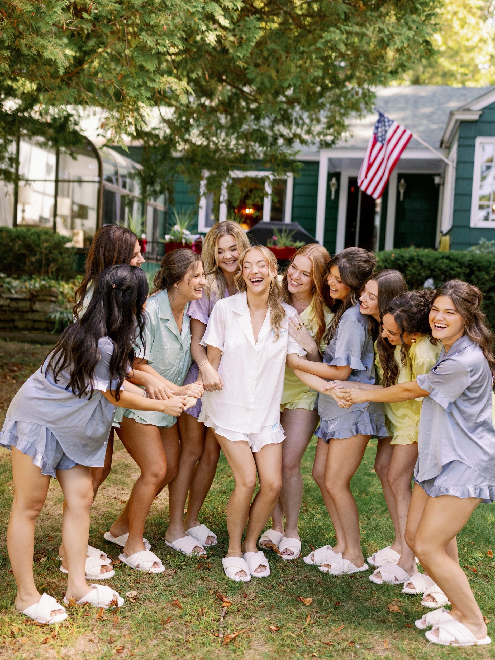A newlywed laughing with their wedding party in matching pajamas 