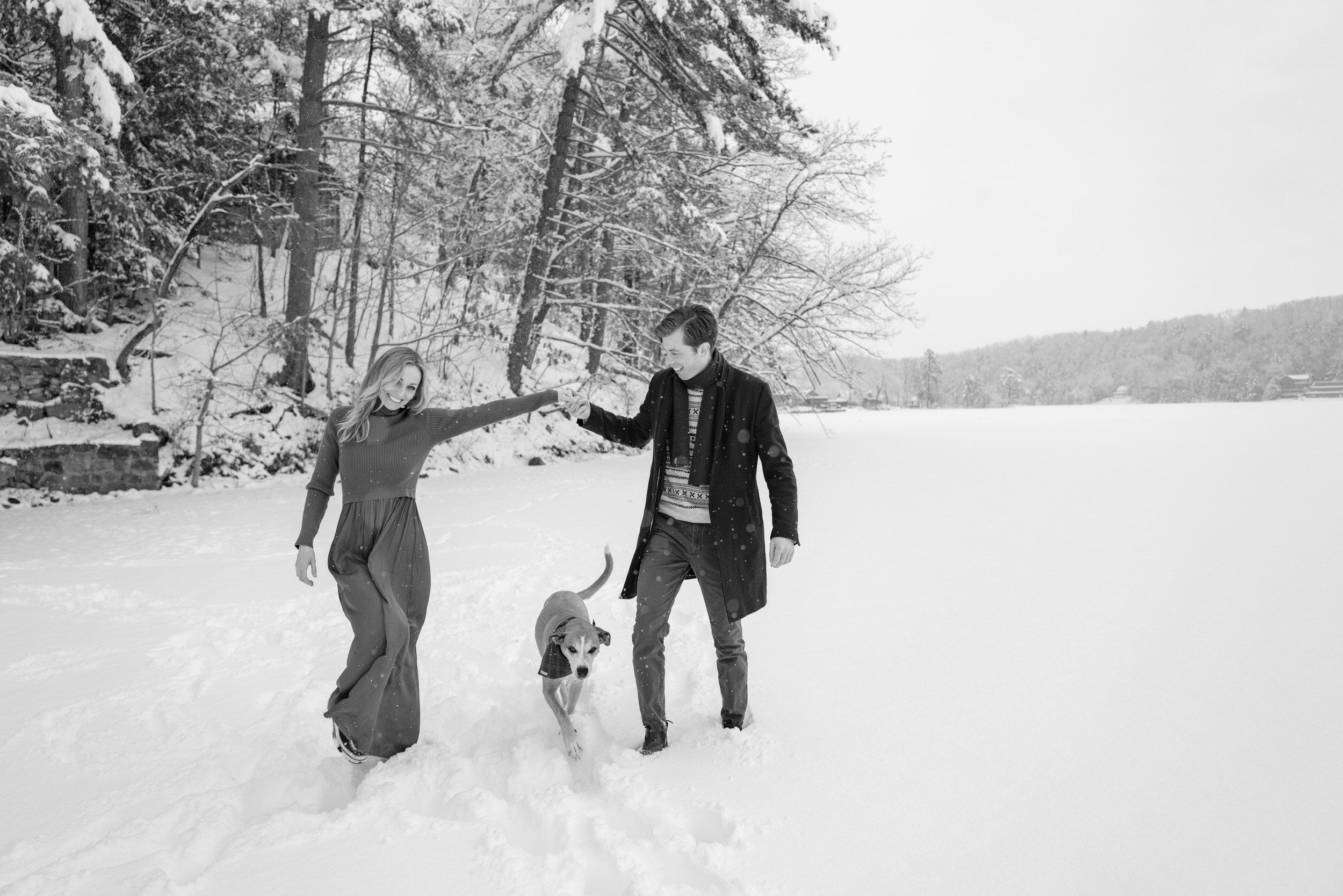 A couple walking in a snowy park with their dog 