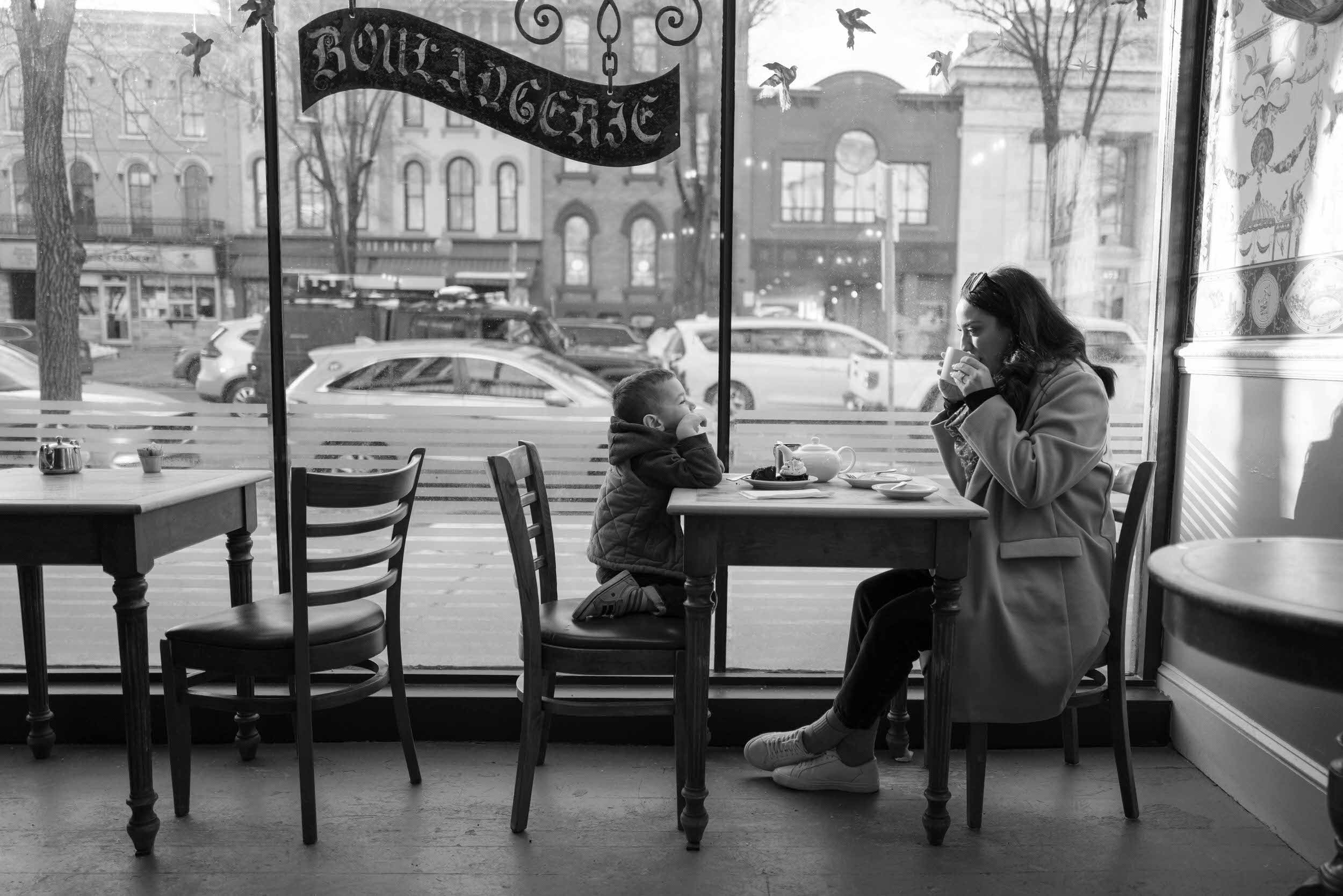 A parent and their child sitting at a table at a cafe together 