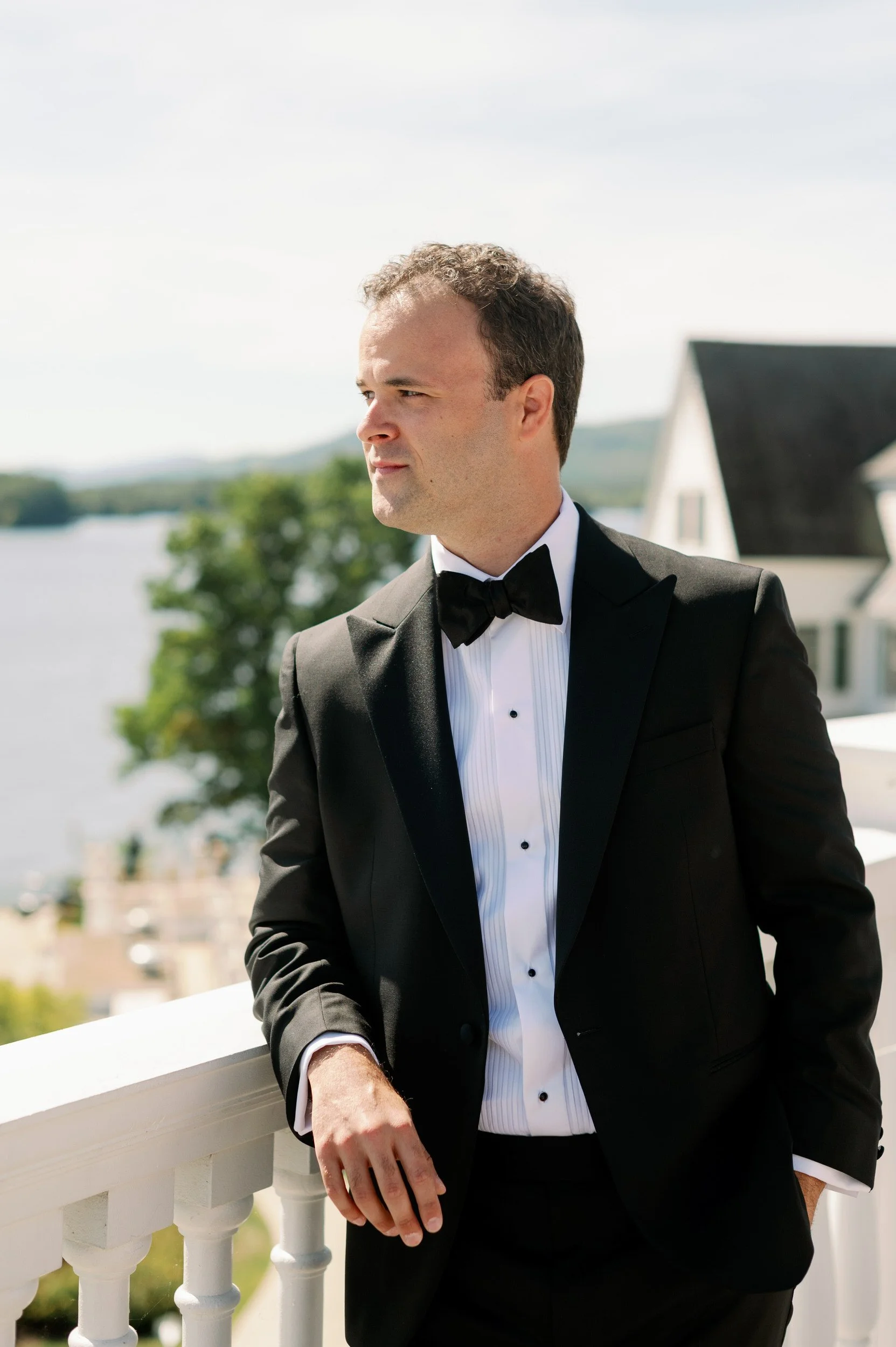 a person in a tux leaning on a balcony looking off into the distance 
