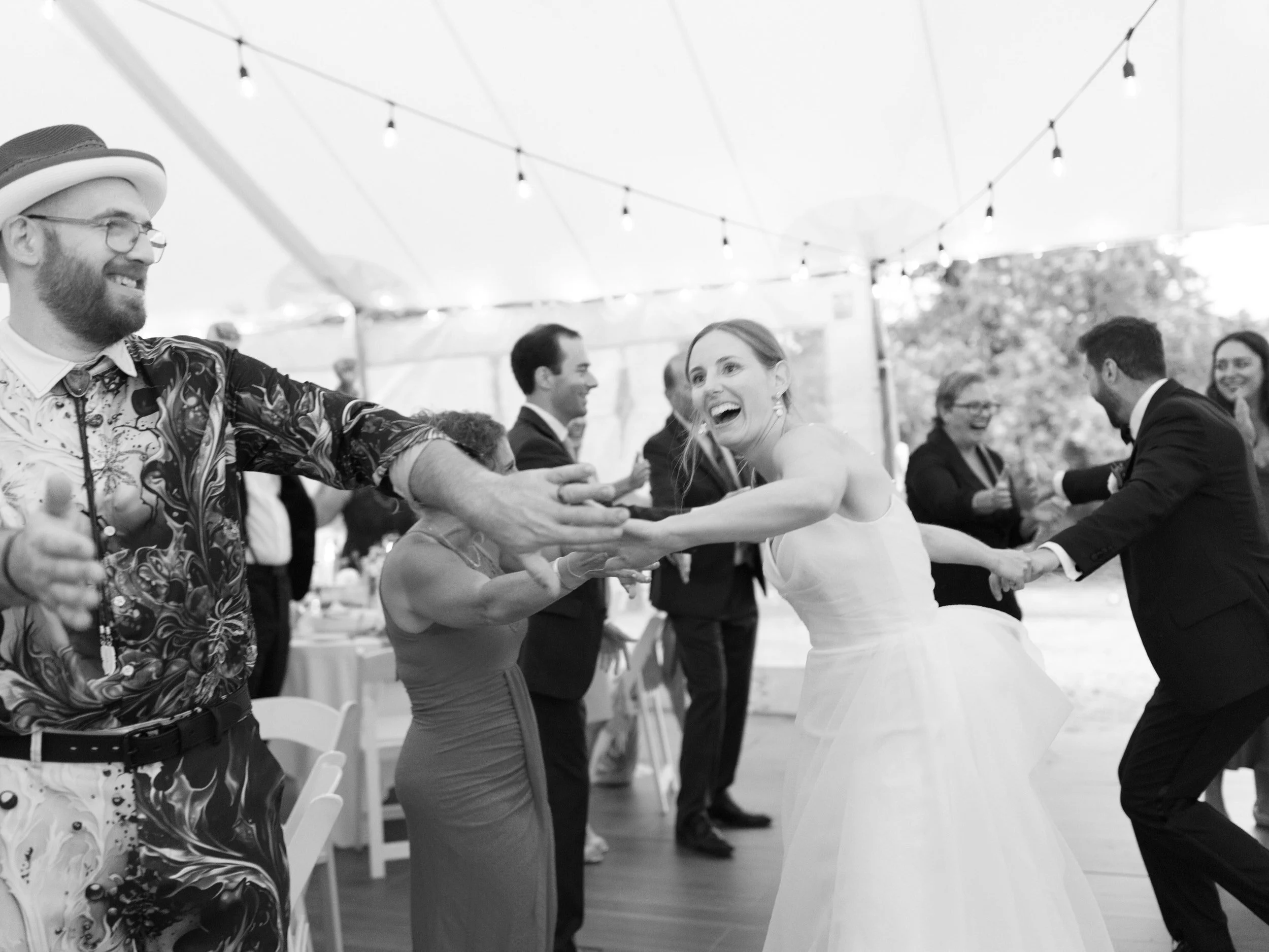 A newlywed dancing at their wedding reception with guests 