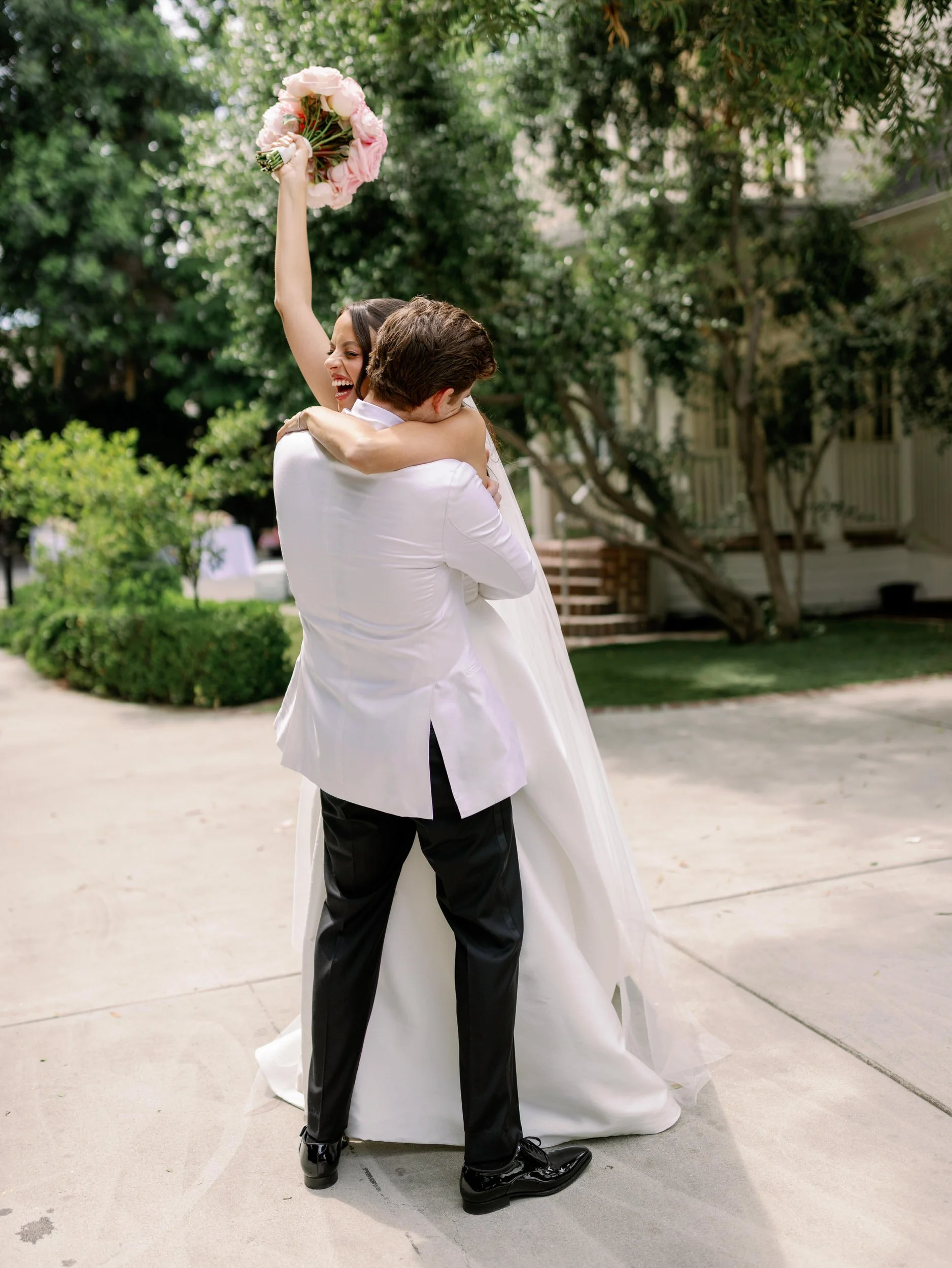  A newlywed hugging their partner and lifting them up as they smile  
