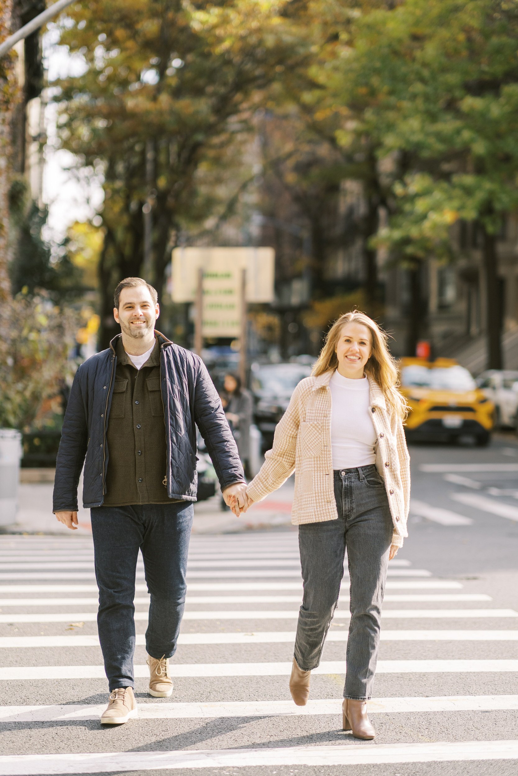 A couple holding hands and walking across a crosswalk 