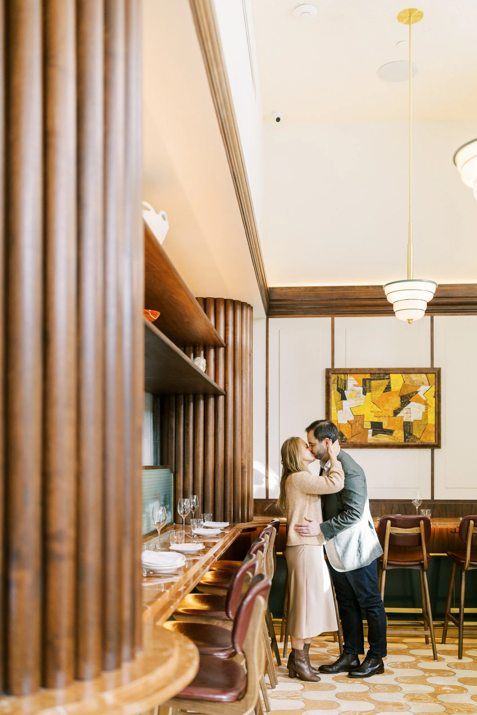 A couple kissing by the bar in an empty restaurant