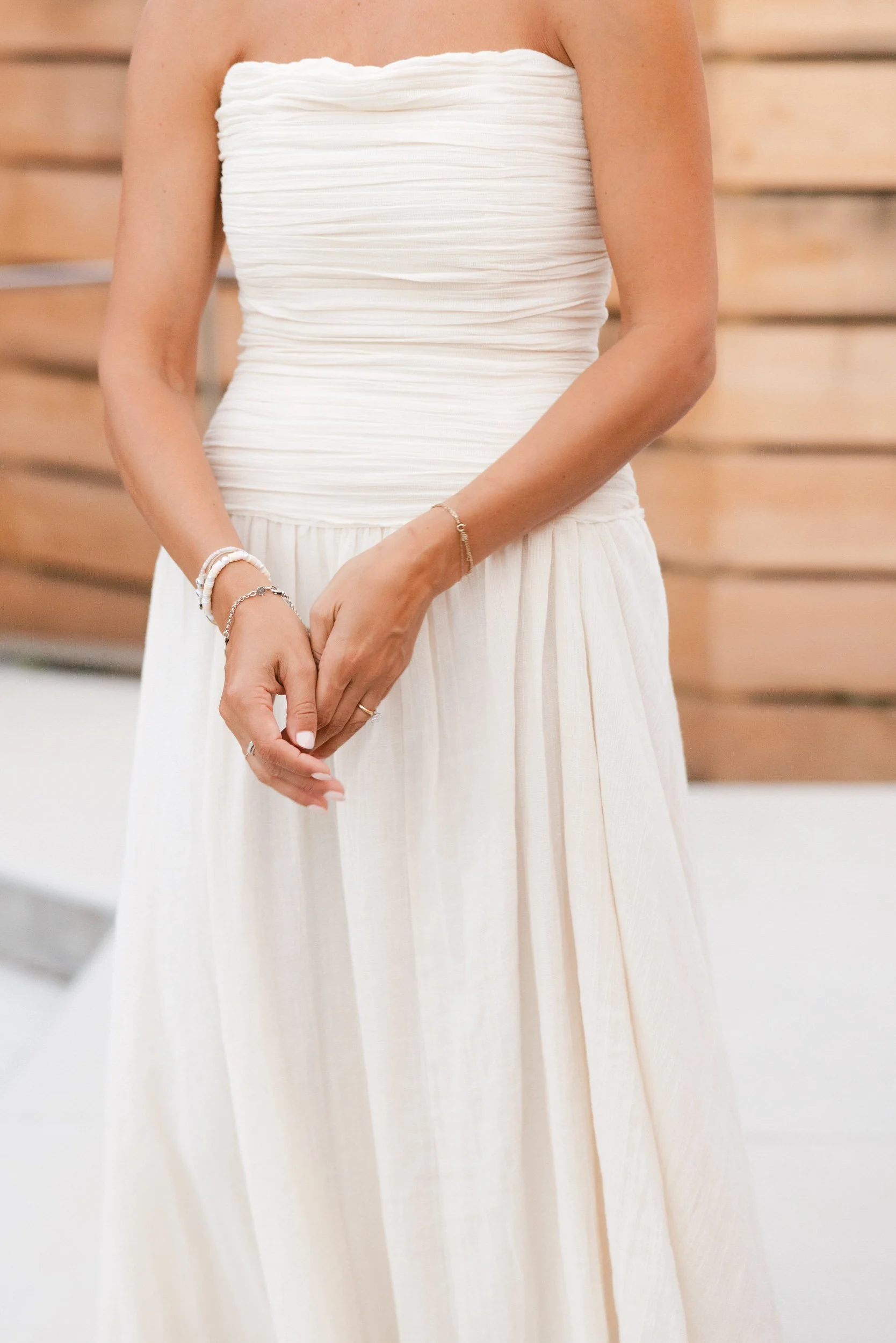 A close up of someone in a wedding dress holding their hands in front of themselves 