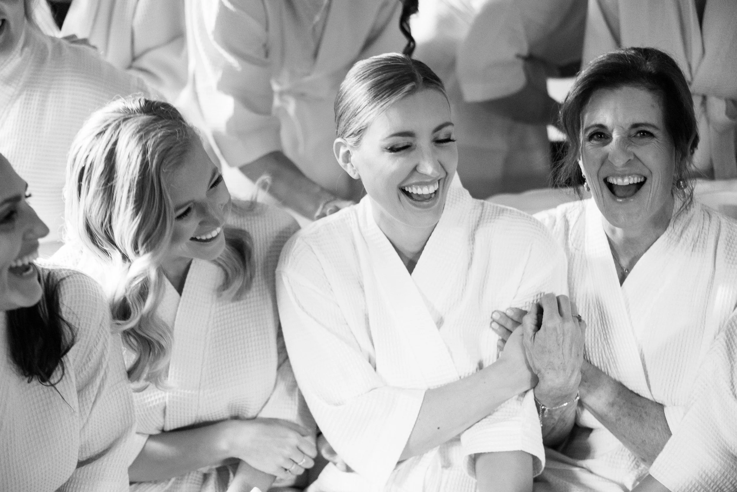 A person laughing with their wedding party as they sit on a couch together 