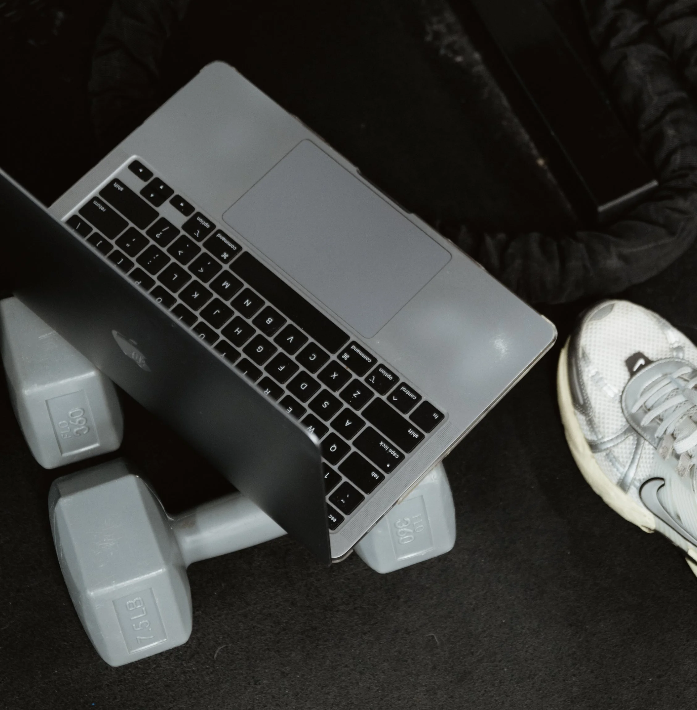 Open laptop laying on top of two dumbbells.