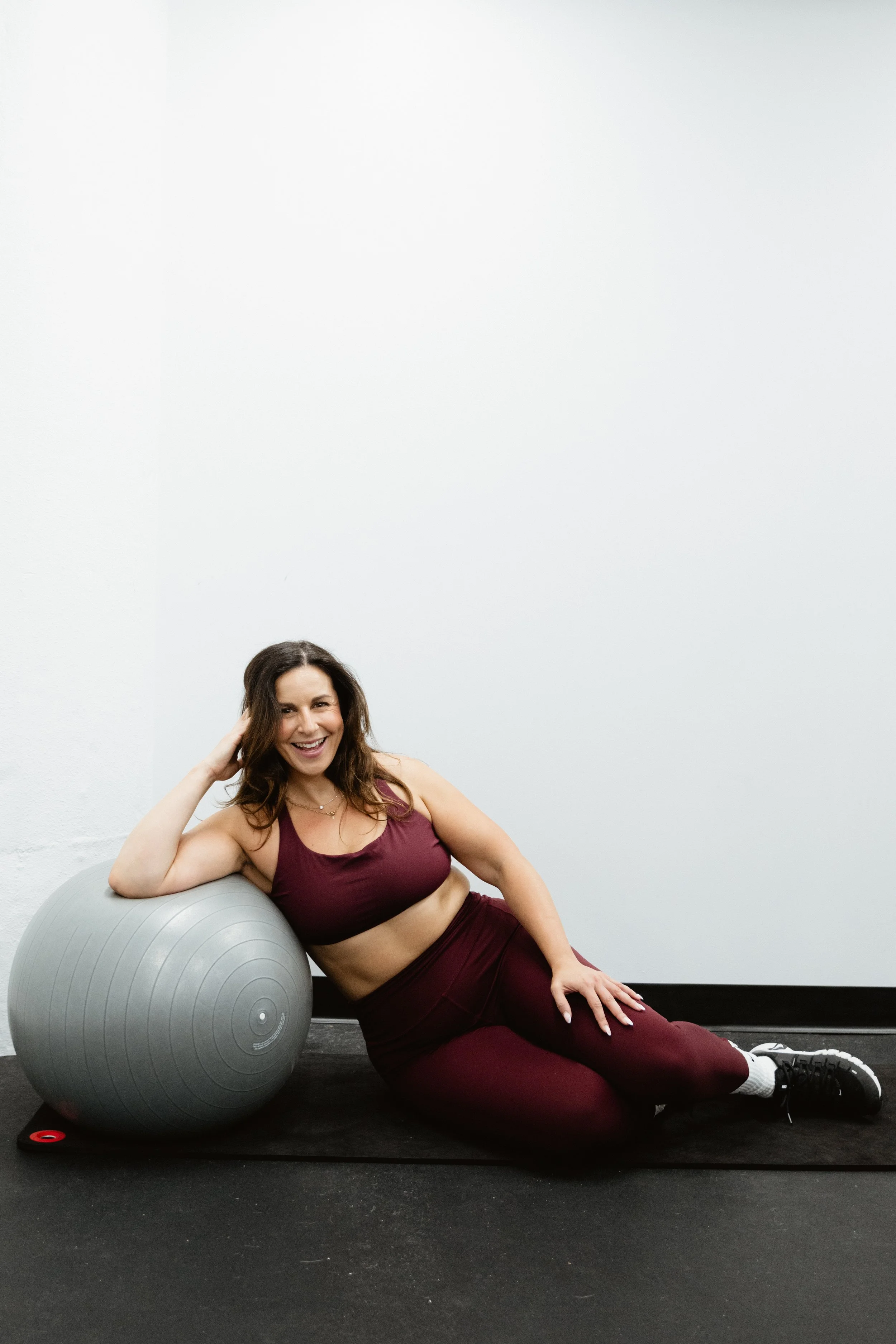 Woman smiling while leaning on a yoga ball
