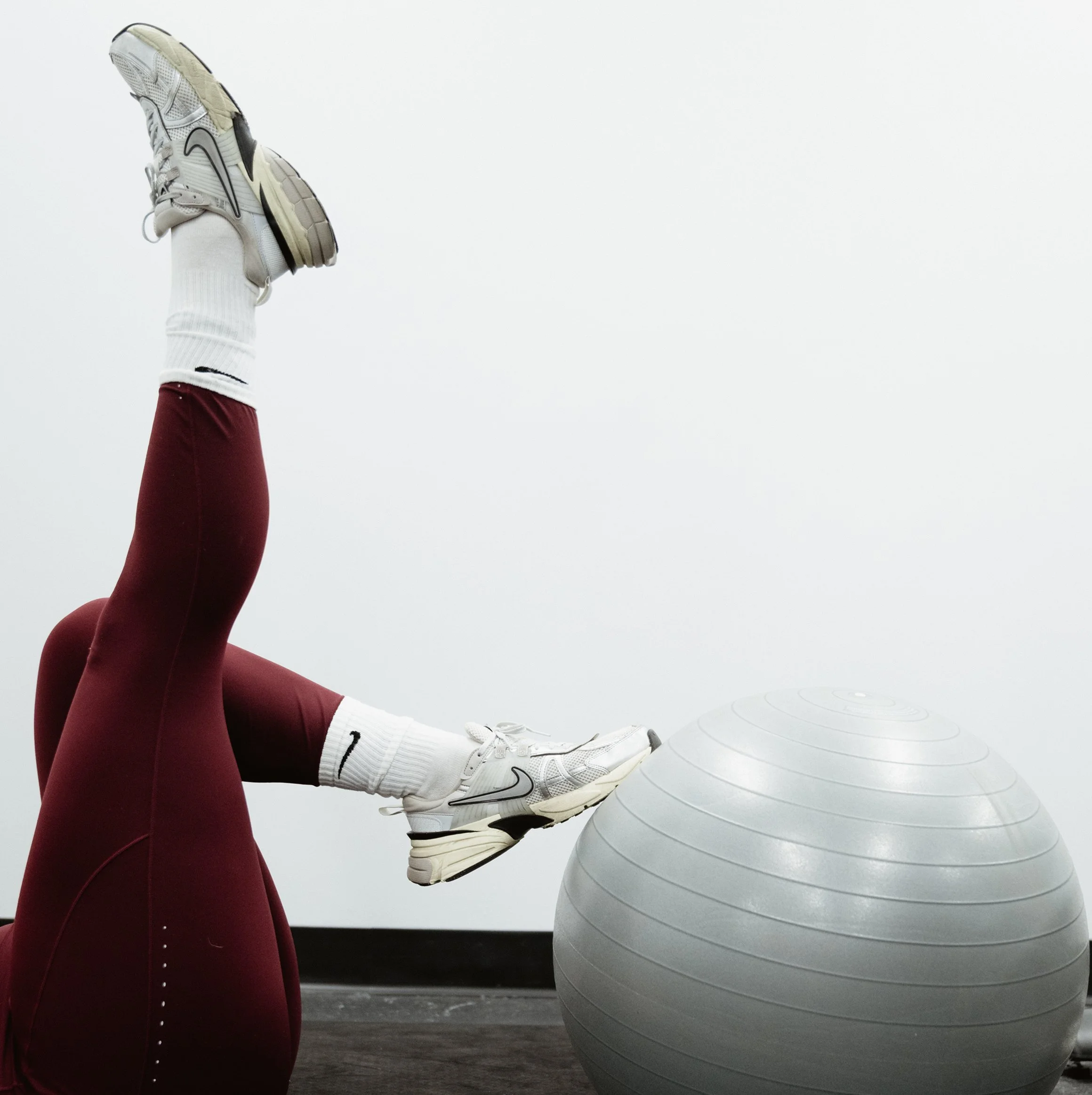 One foot raised towards the sky and another foot tapping a yoga ball.