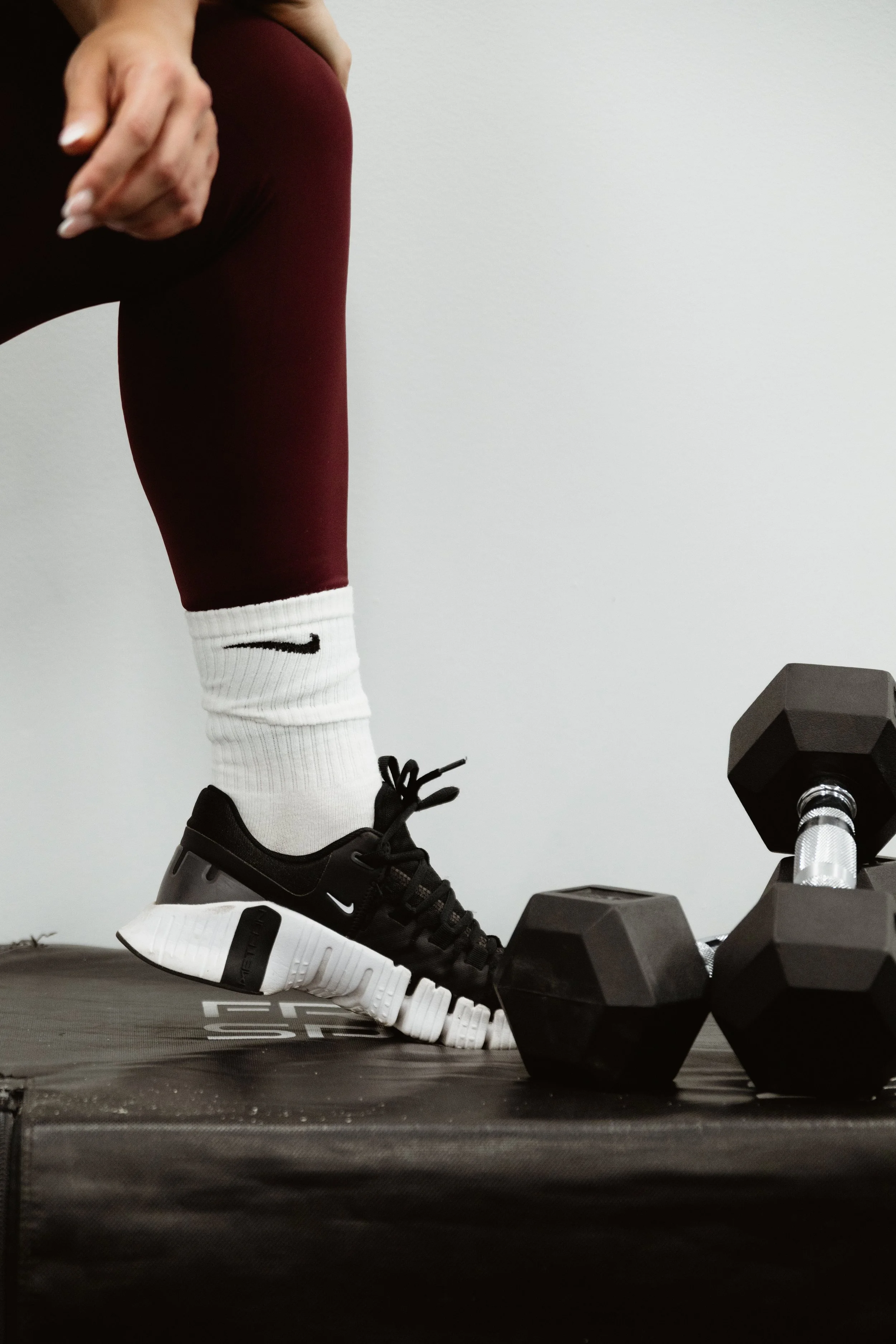 Close up of person in sneakers and two dumbbells.