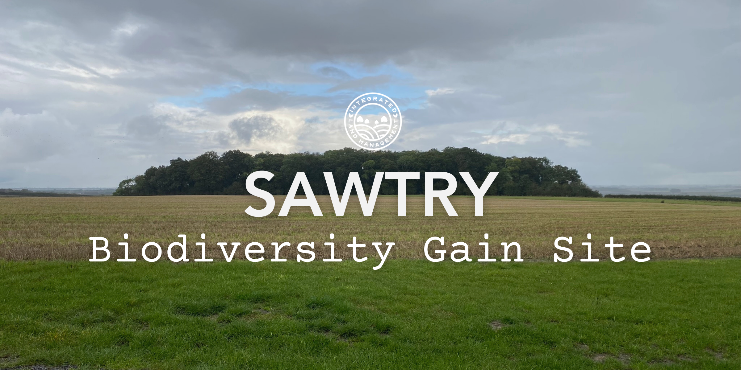Sawtry Biodiversity Gain Site in Huntingdonshire showing arable farmland and grassland with a woodland copse under a cloudy sky in the Bedfordshire and Cambridgeshire Claylands NCA.