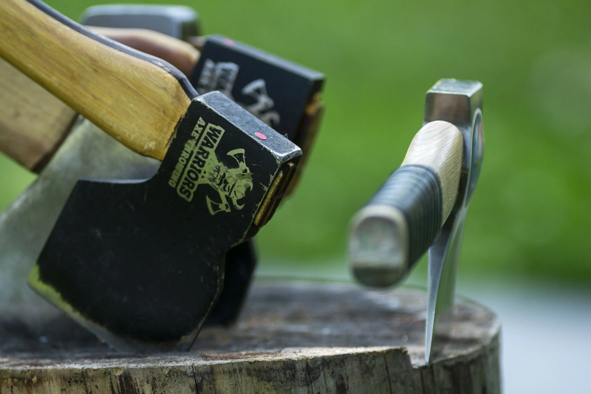 A collection of outdoor knives and sharp tools resting on a tree stump.
