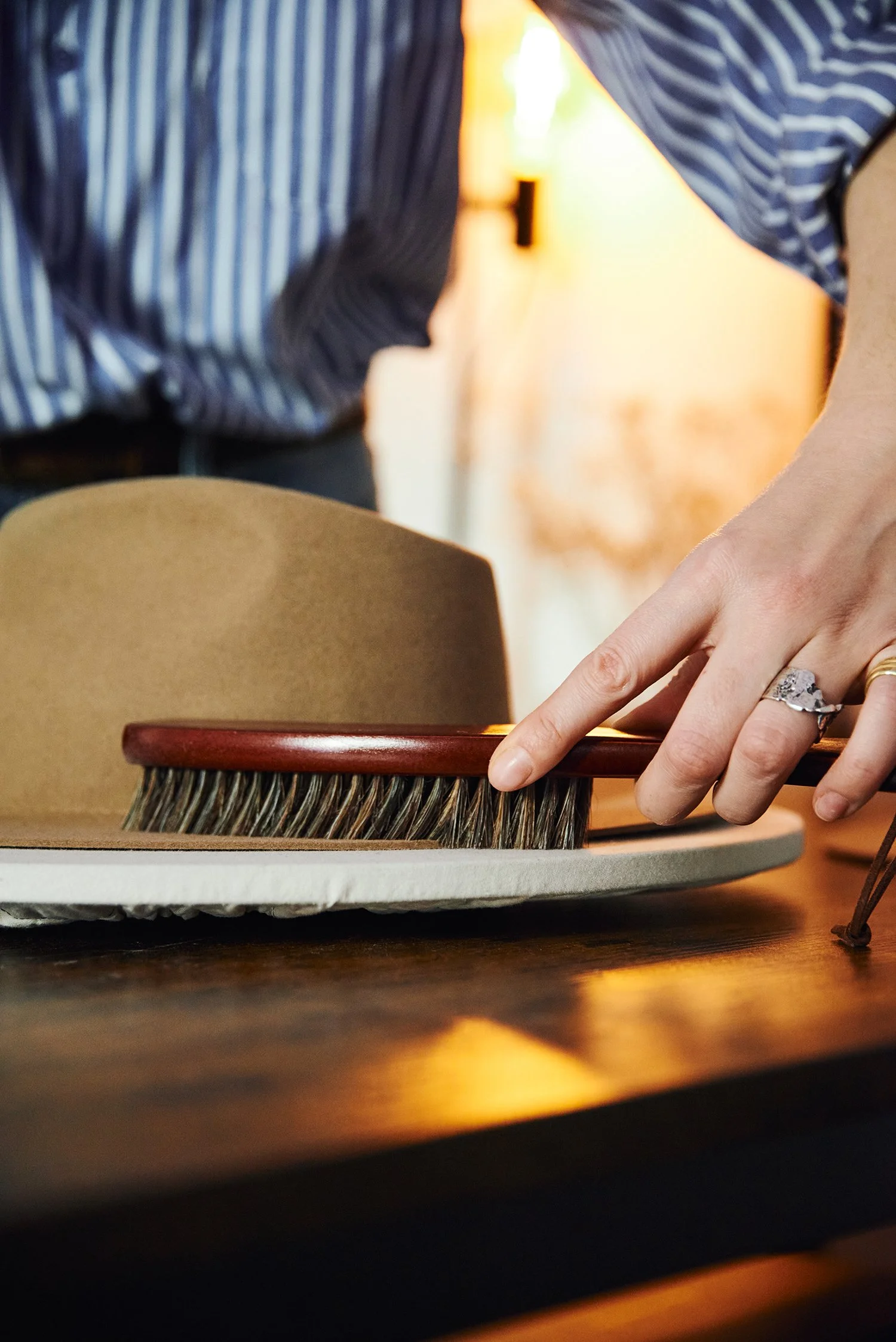 Cleaning a felt hat using a soft brush during hat care.