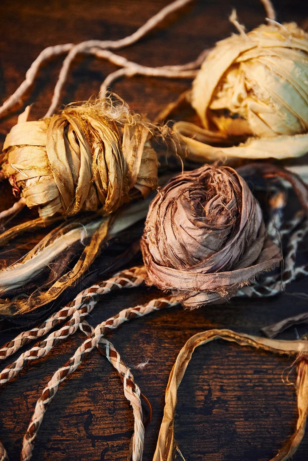 Dried artichoke hearts with tied stems, arranged on a dark wooden surface.