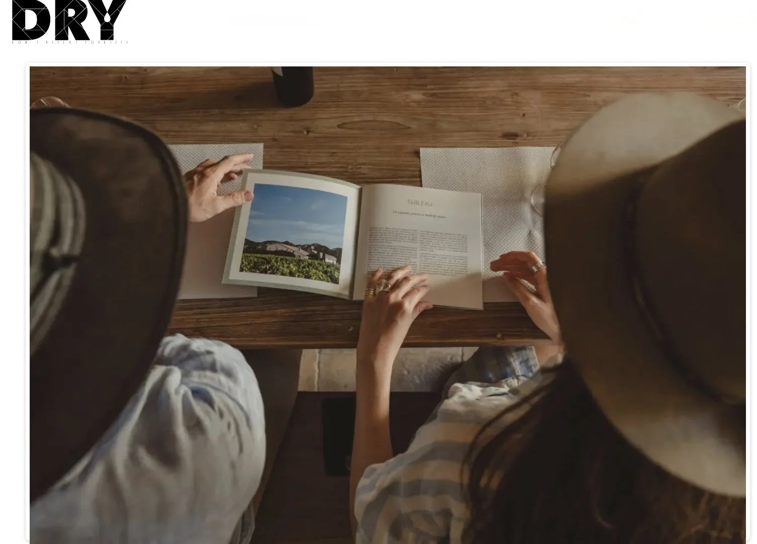 Man and a woman wearing wide-brimmed hats seated on a table.