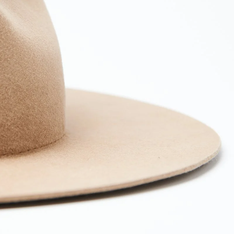 Flat brim detail of a beige felt hat on a white background.