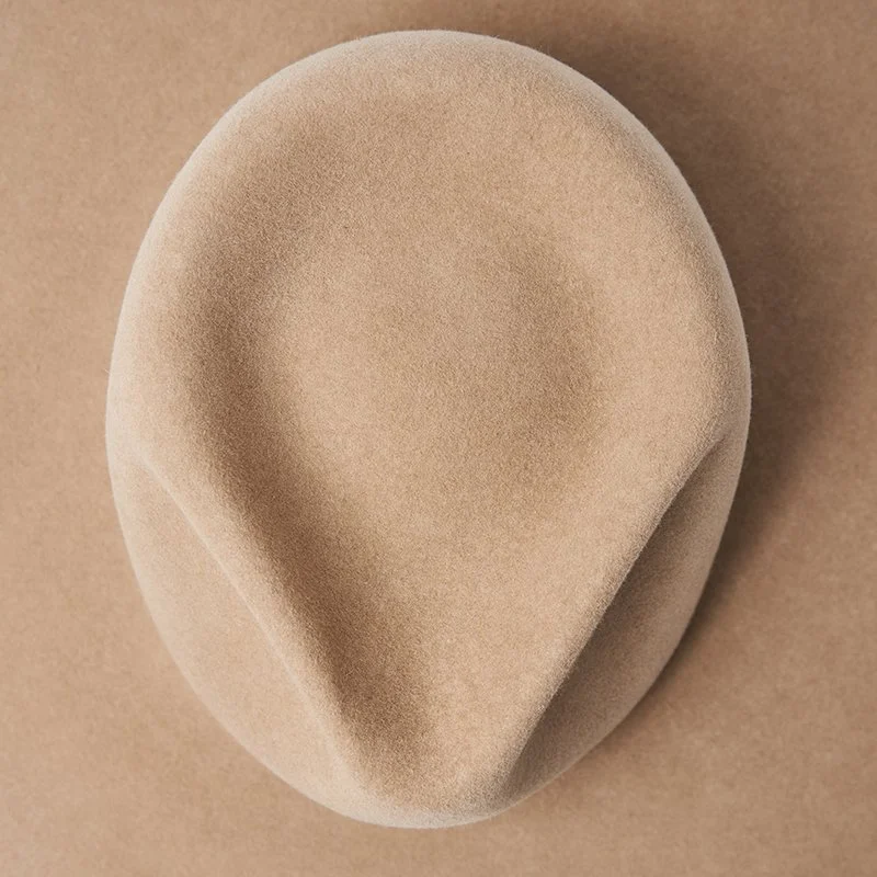 Hand-shaped beige felt fedora crown showing defined crease.