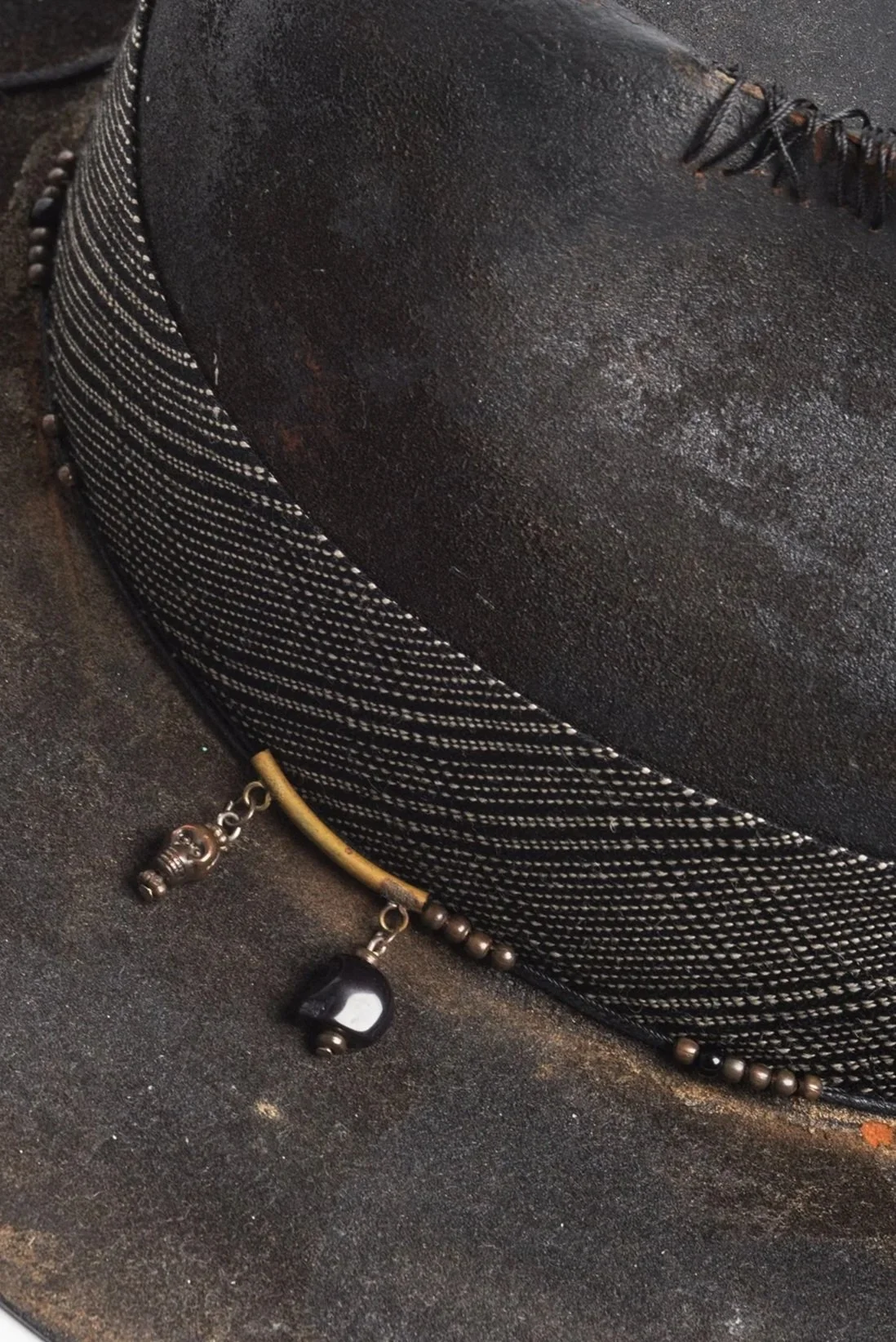 Close-up image of a black, textured shoe with decorative beads and charms attached, on a dark surface.