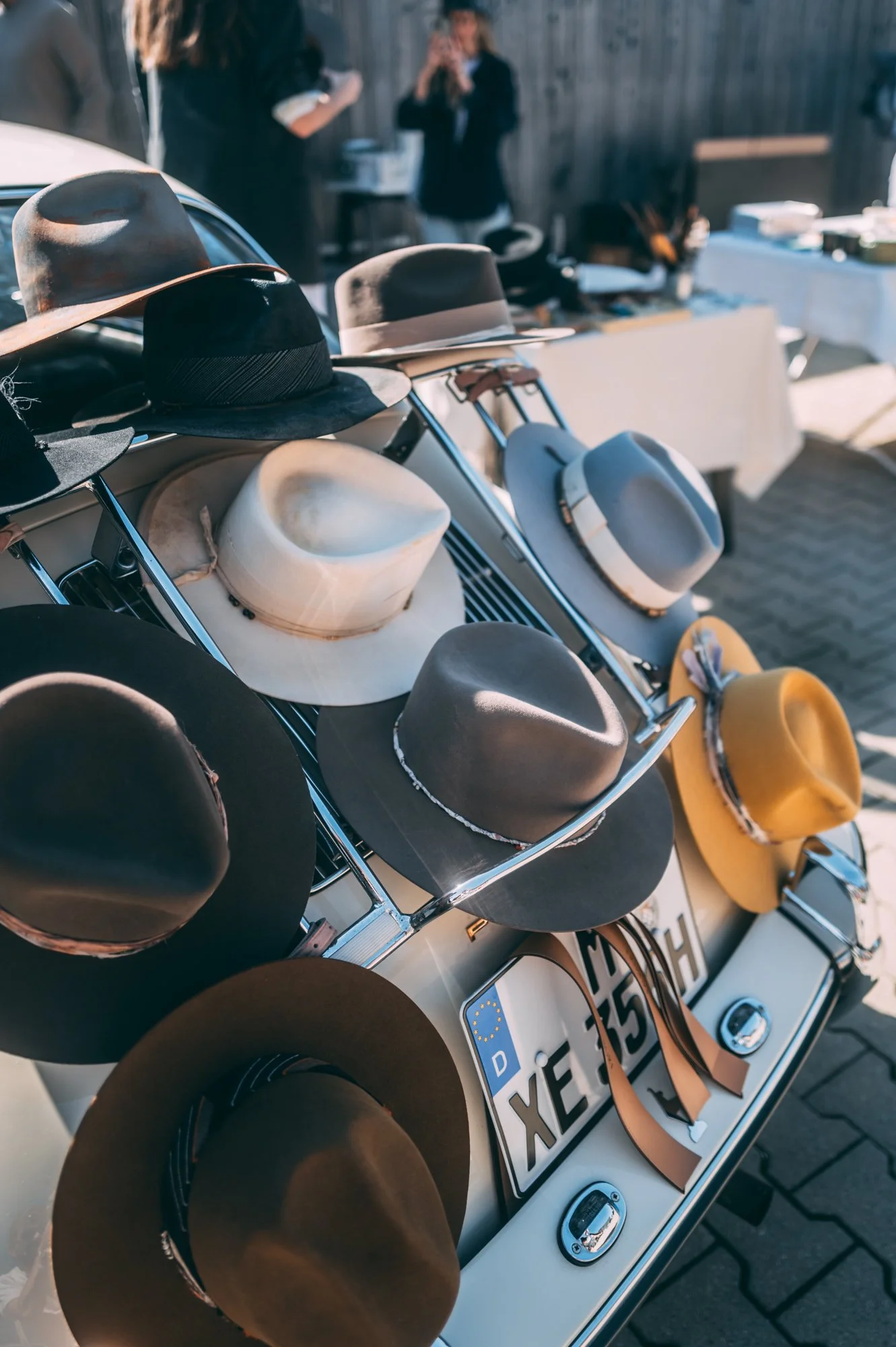 a selection of handmade  hats on the trunk of a vintage car