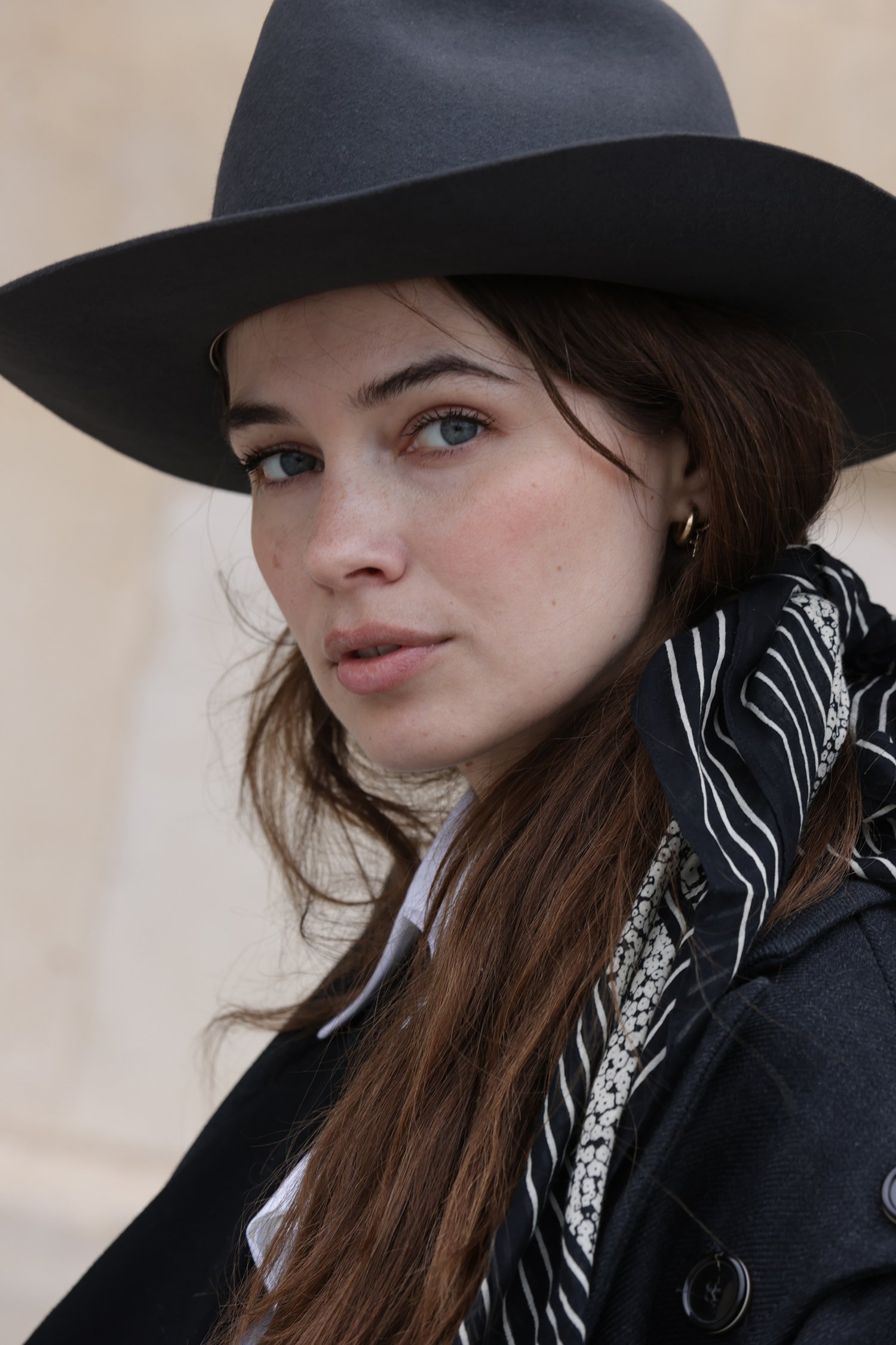 Close-up portrait of a woman wearing a wide-brimmed hat, looking toward the camera.