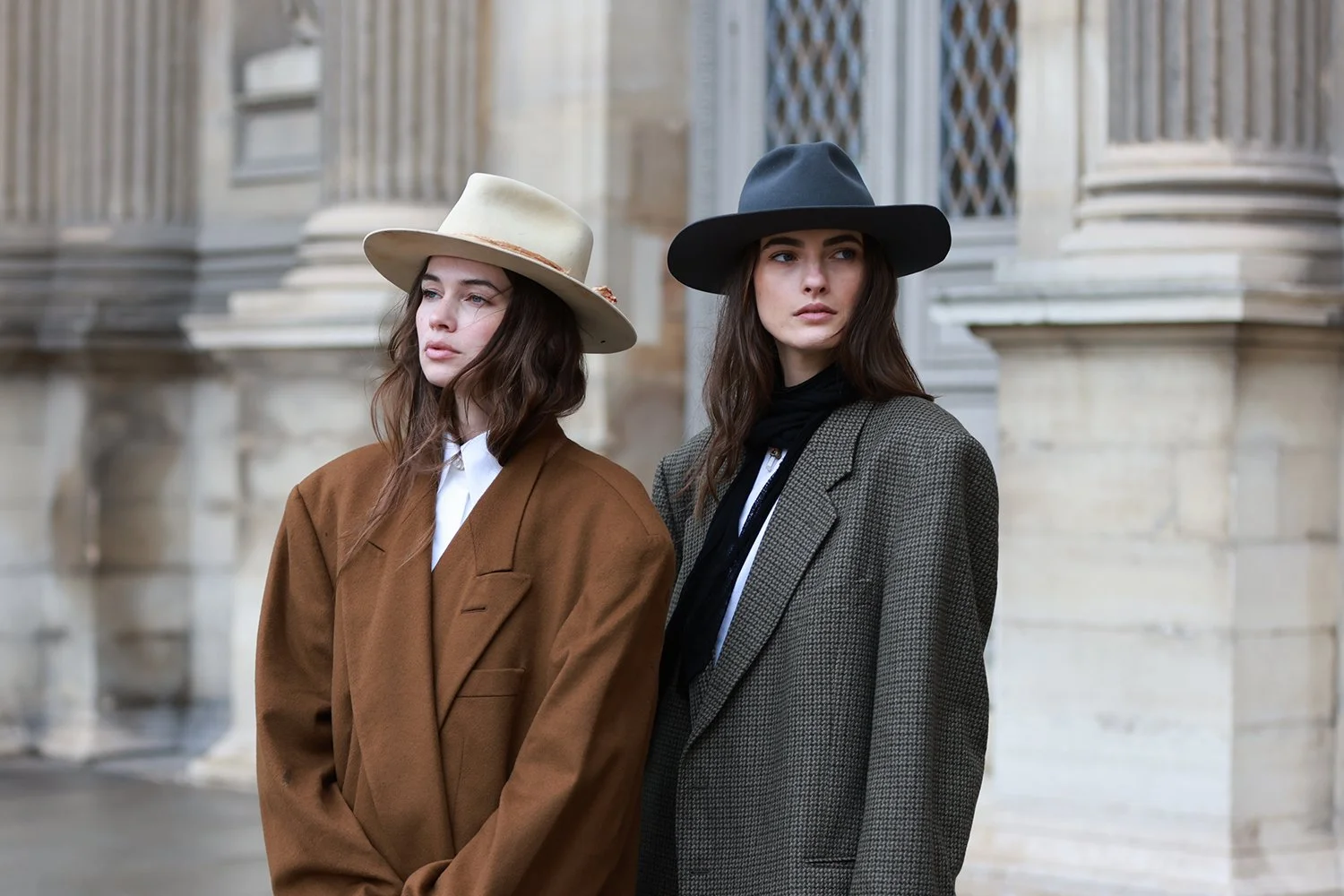 Two women standing outdoors, wearing handcrafted hats and coats.