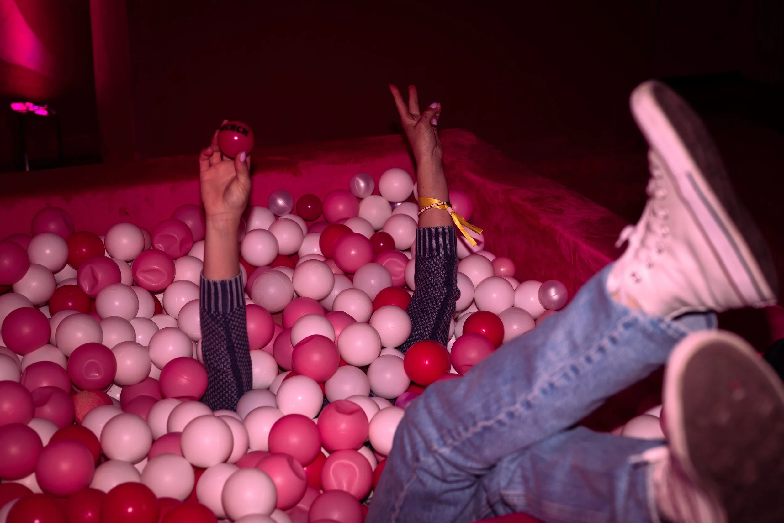 Guest playfully falls into a pink-and-white ball pit at a Red Bull Peach Edition pop-up experience.