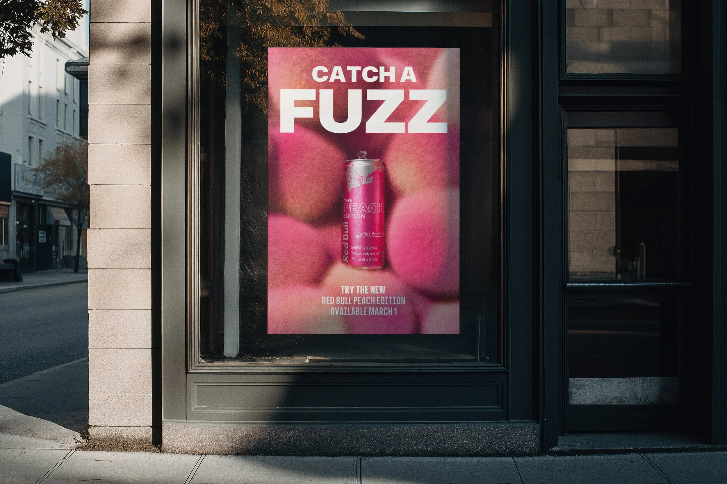 Red Bull Peach Edition ‘Catch a Fuzz’ ad displayed in a storefront window, featuring a pink can against a fuzzy pink background