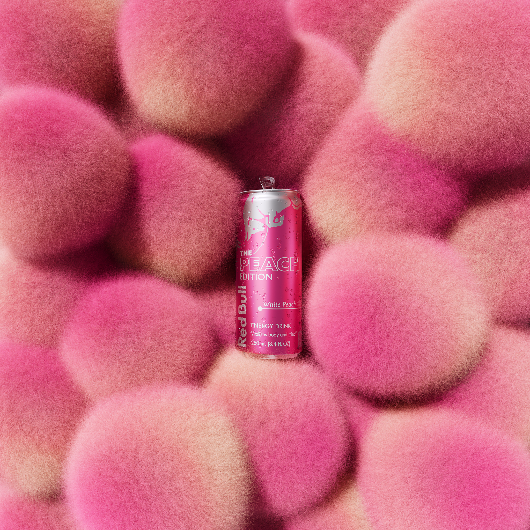 Red Bull Peach Edition can surrounded by soft, fuzzy pink and peach spheres.