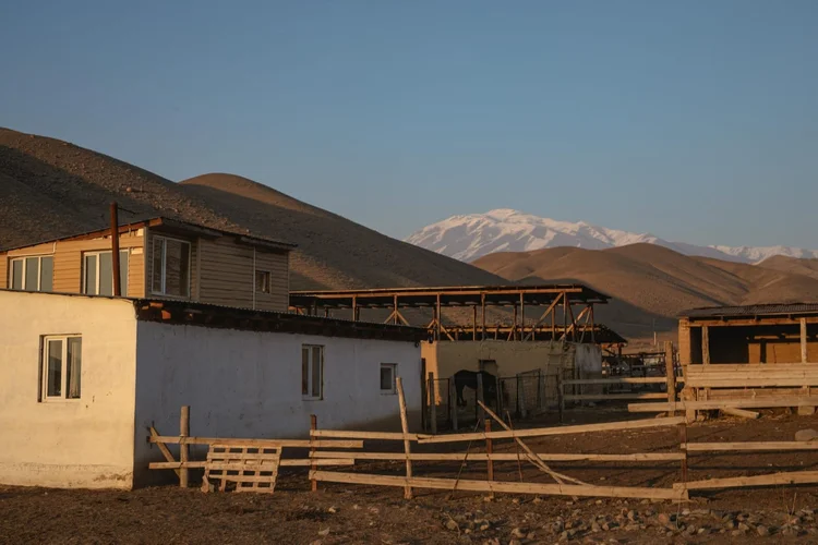 The farm buildings at dusk, with snowy peaks behind