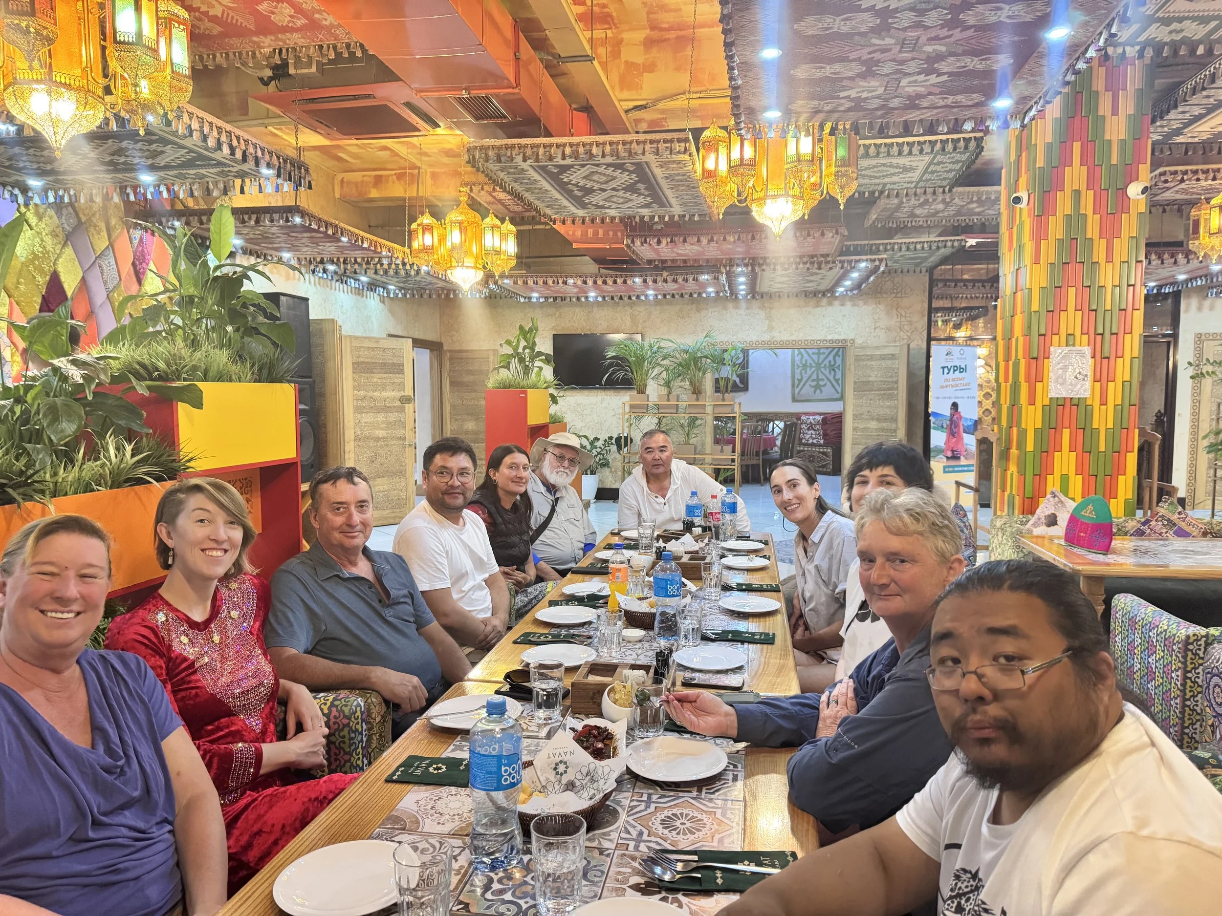 A group of people smiling together at a long restaurant table