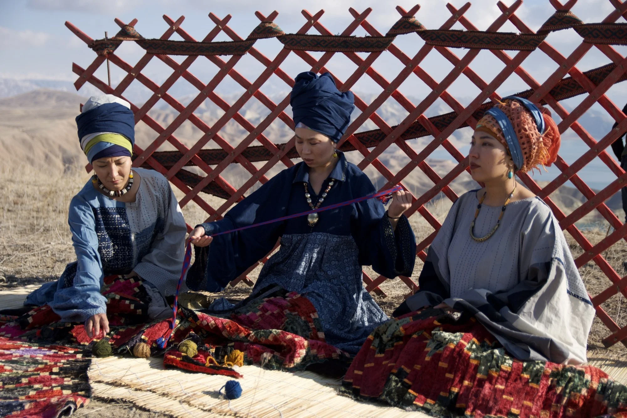 Des femmes kirghizes en tenue traditionnelle avec des textiles brodés dans une yourte