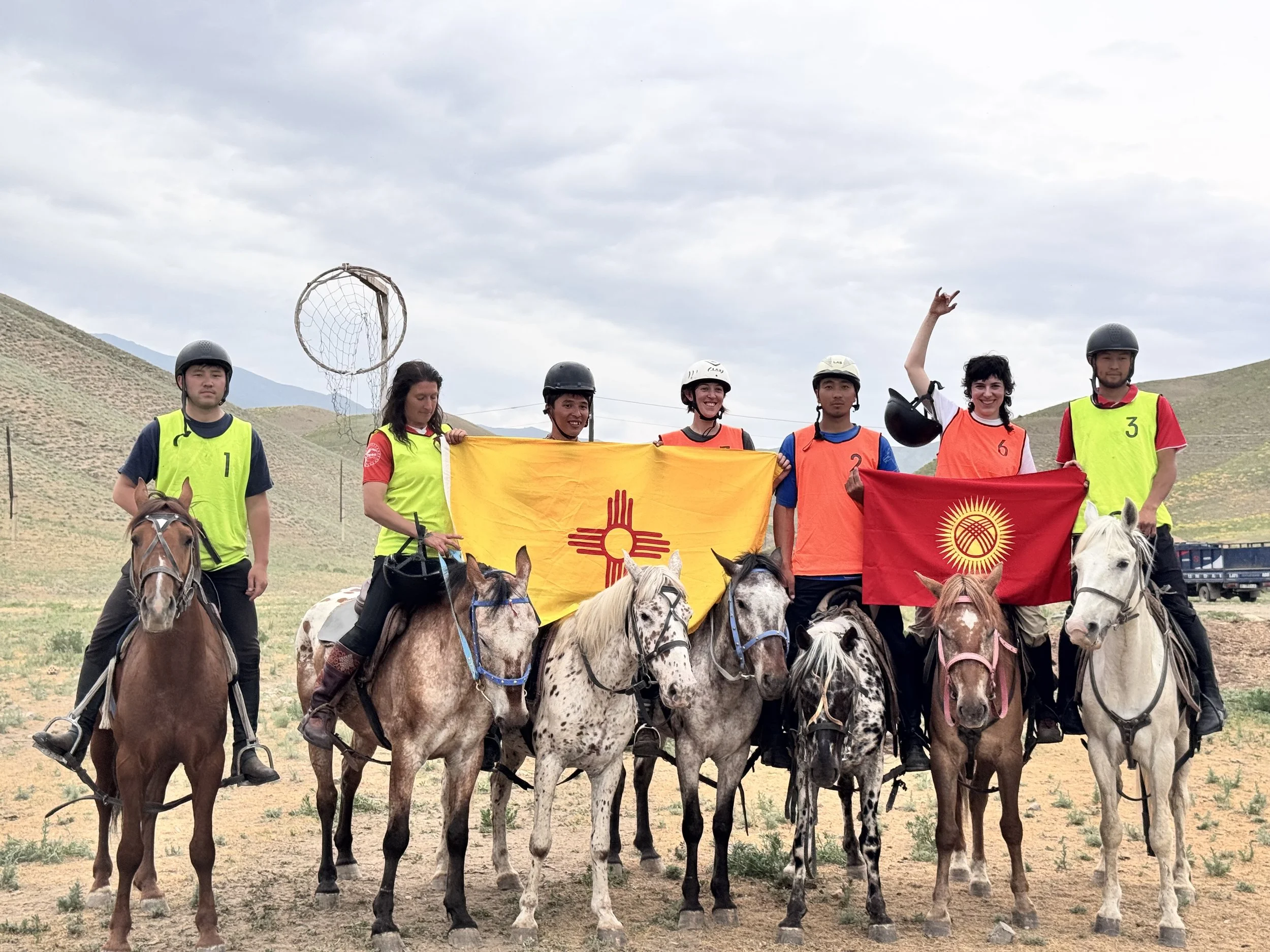 Riders on Chaar horses holding flags and posing for a photo on a hillside