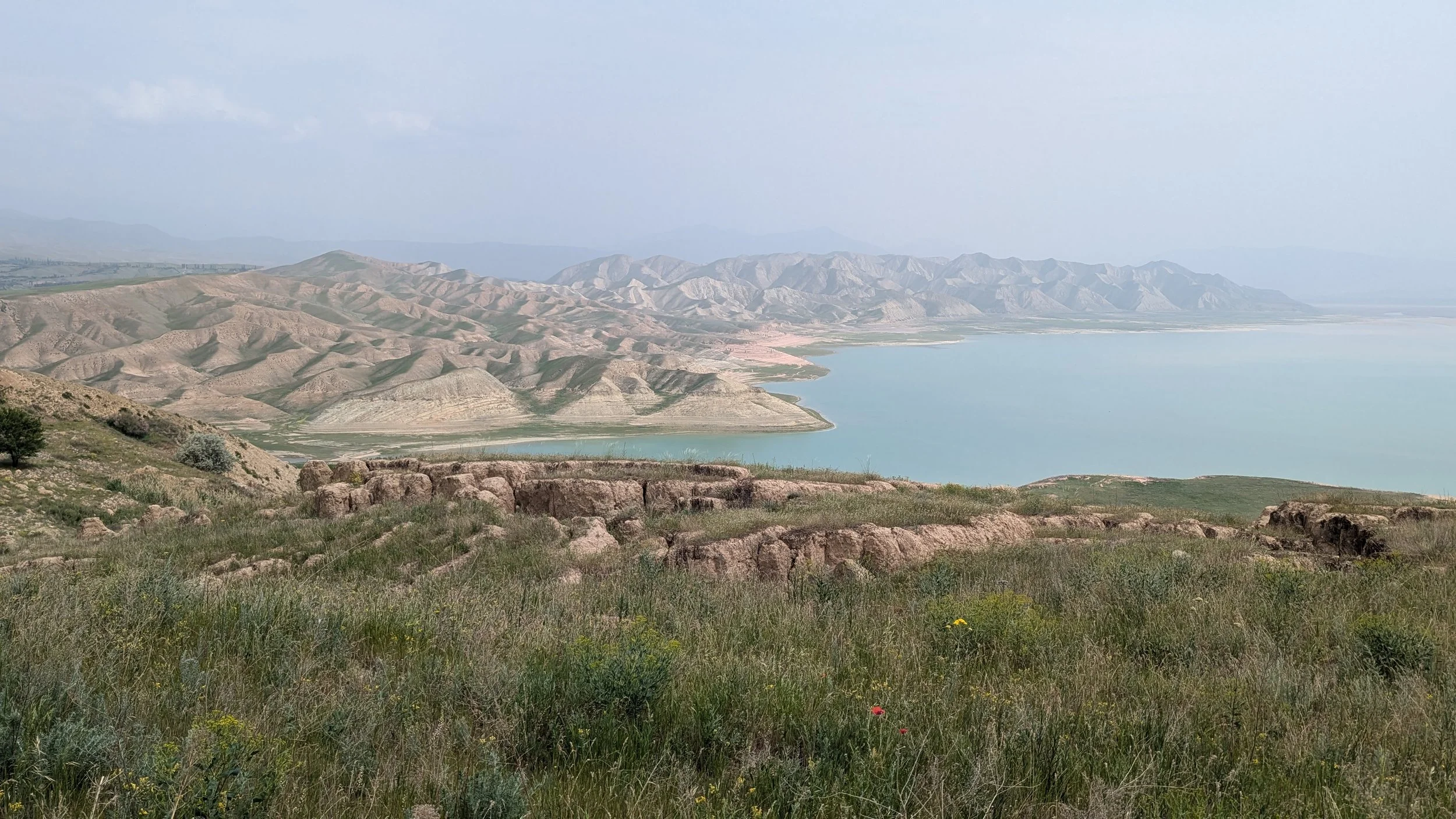 View over a reservoir and dry rolling hills from a grassy ridge