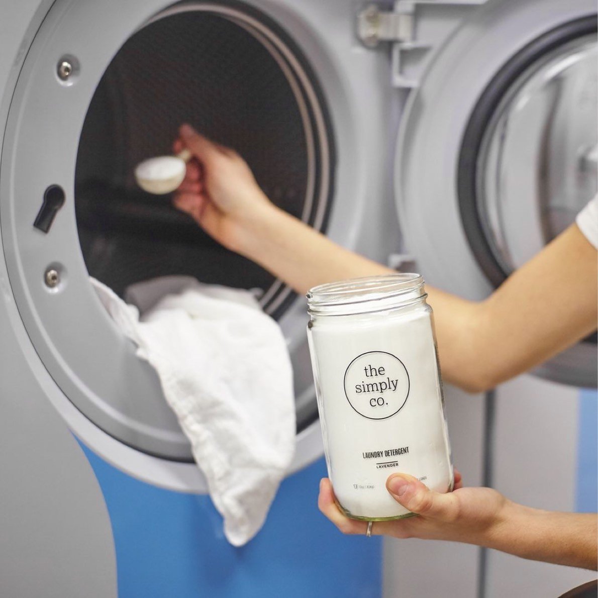 Woman scooping laundry detergent into washing machine