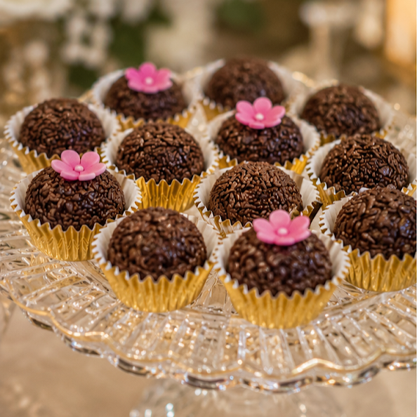 Chocolate truffles with pink flower toppings on a glass tray.