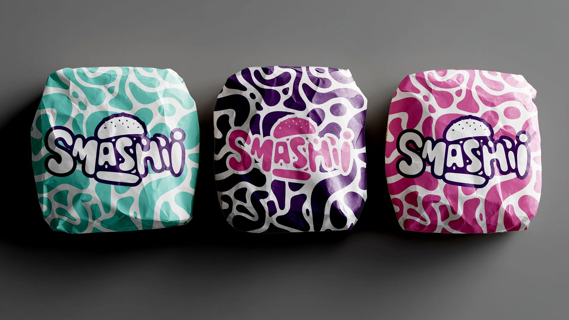 Tre sprøde poser med sushi fra mærket 'Smashi', hver med livligt farvet design: blågrøn, lilla og pink, placeret på en neutral grå baggrund.