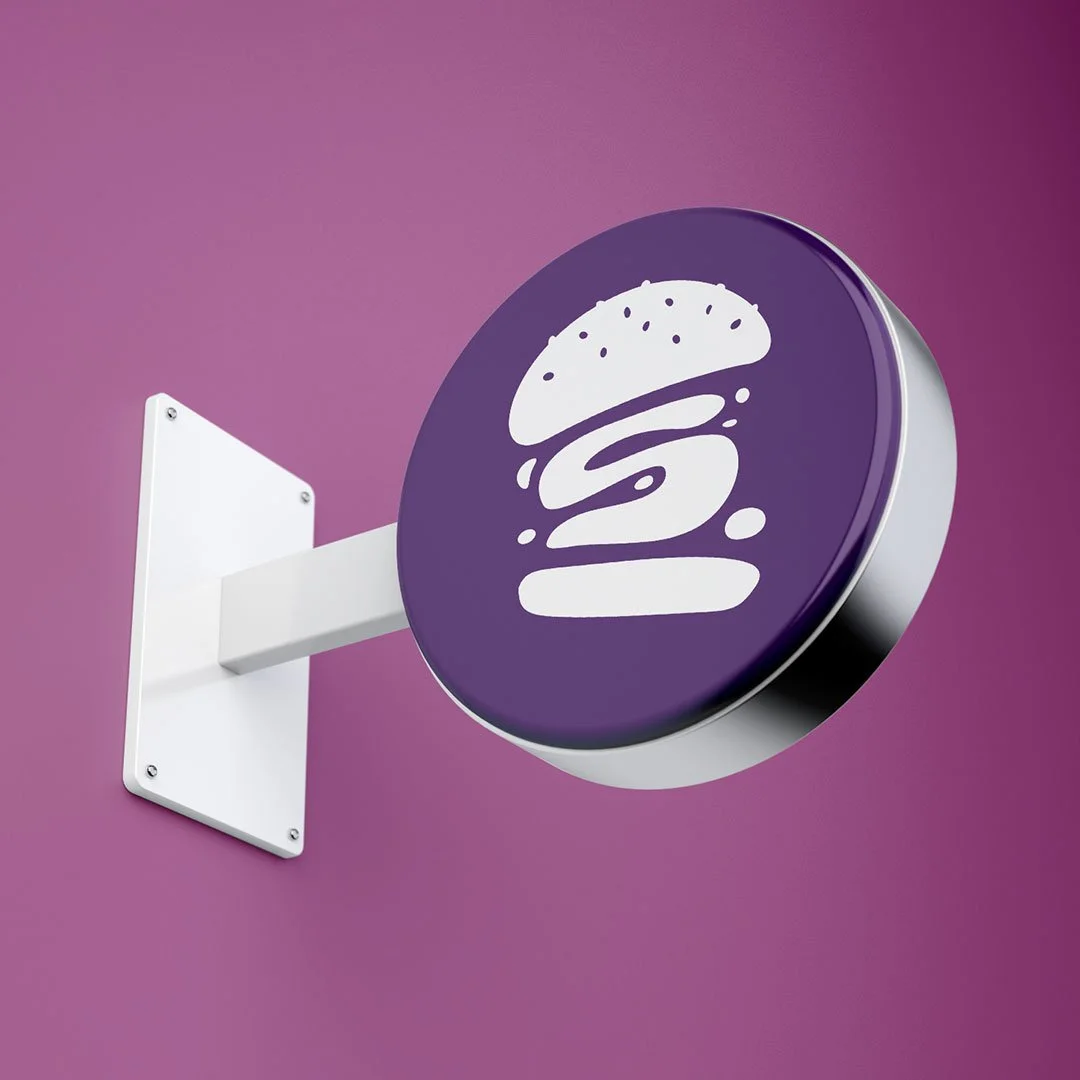En rund skilt med en burger illustration er hængt op på en væg.