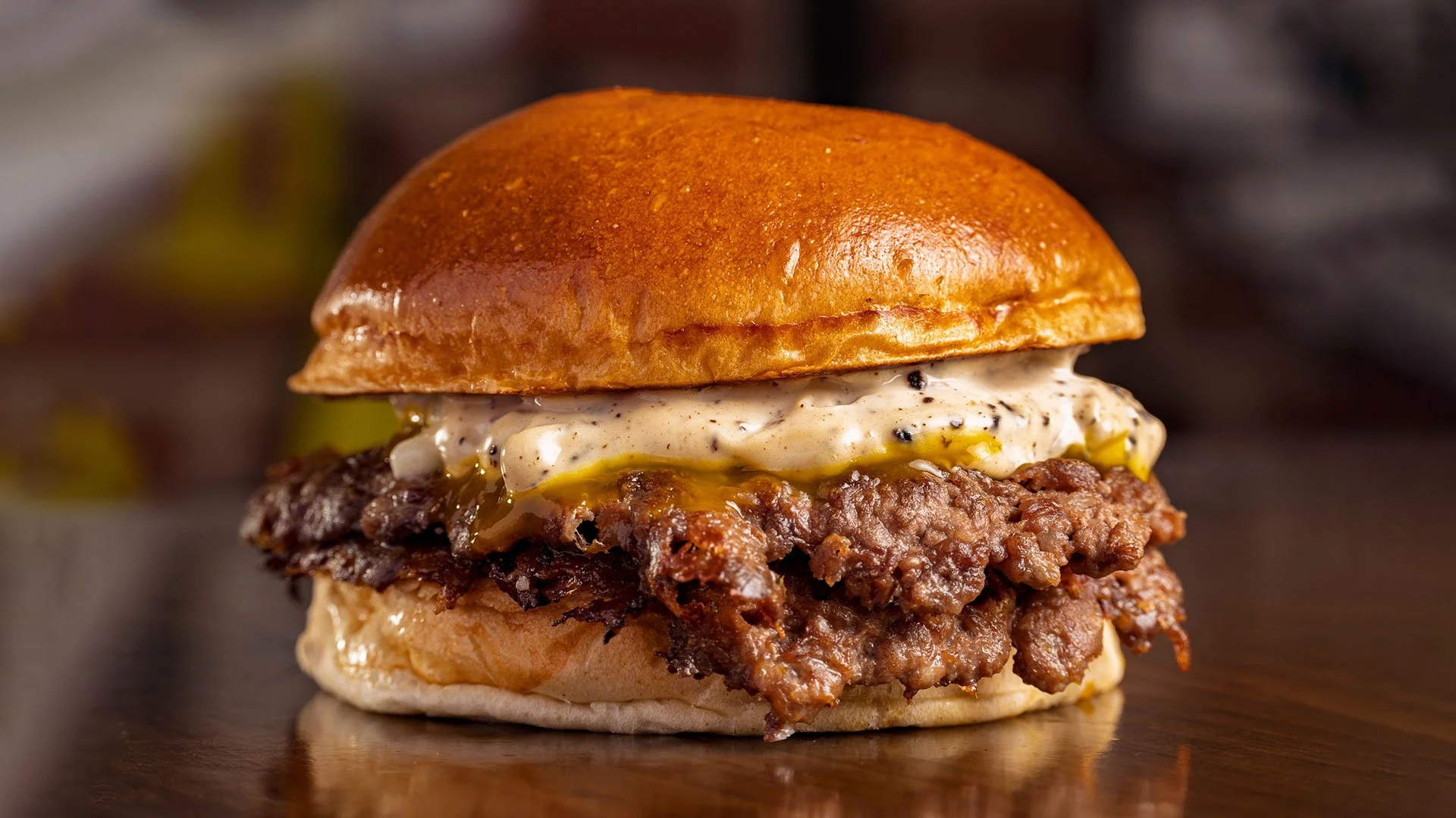 En burger med oksekødsbøf, krydret sauce, ost og en burgerbolle.