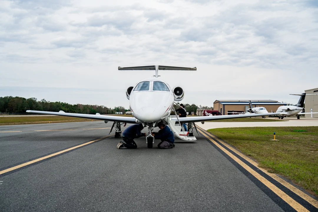 Crew working under an Embraer Phenom 100 on the ramp