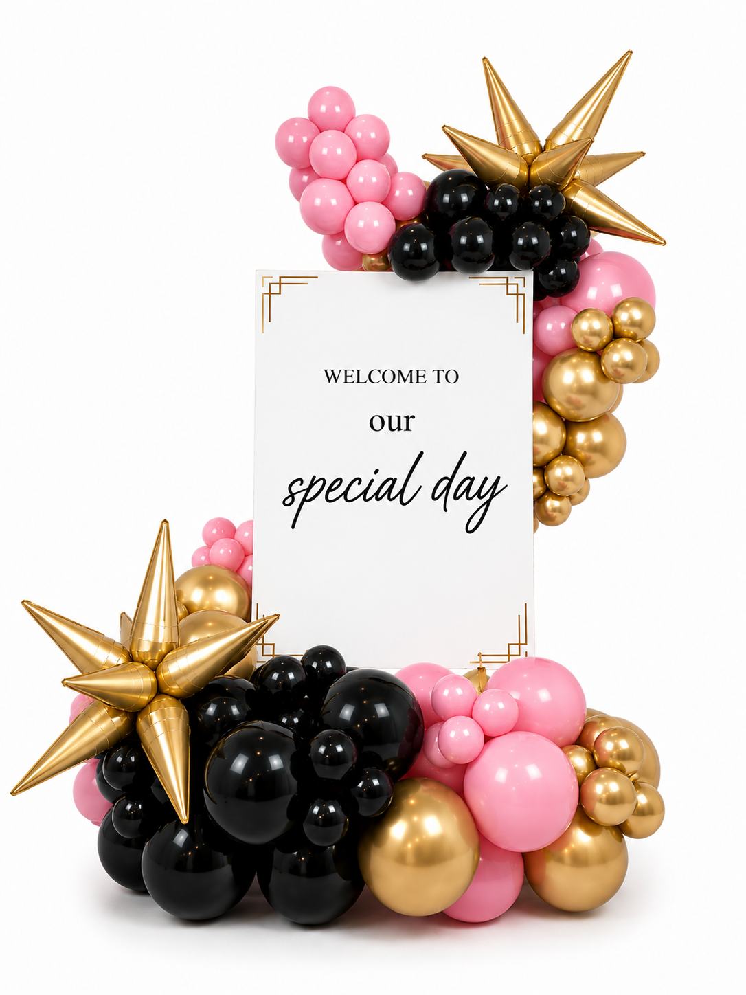 Balloons in pink, black, and gold around a white welcome sign with custom wording on a white acrylic board.