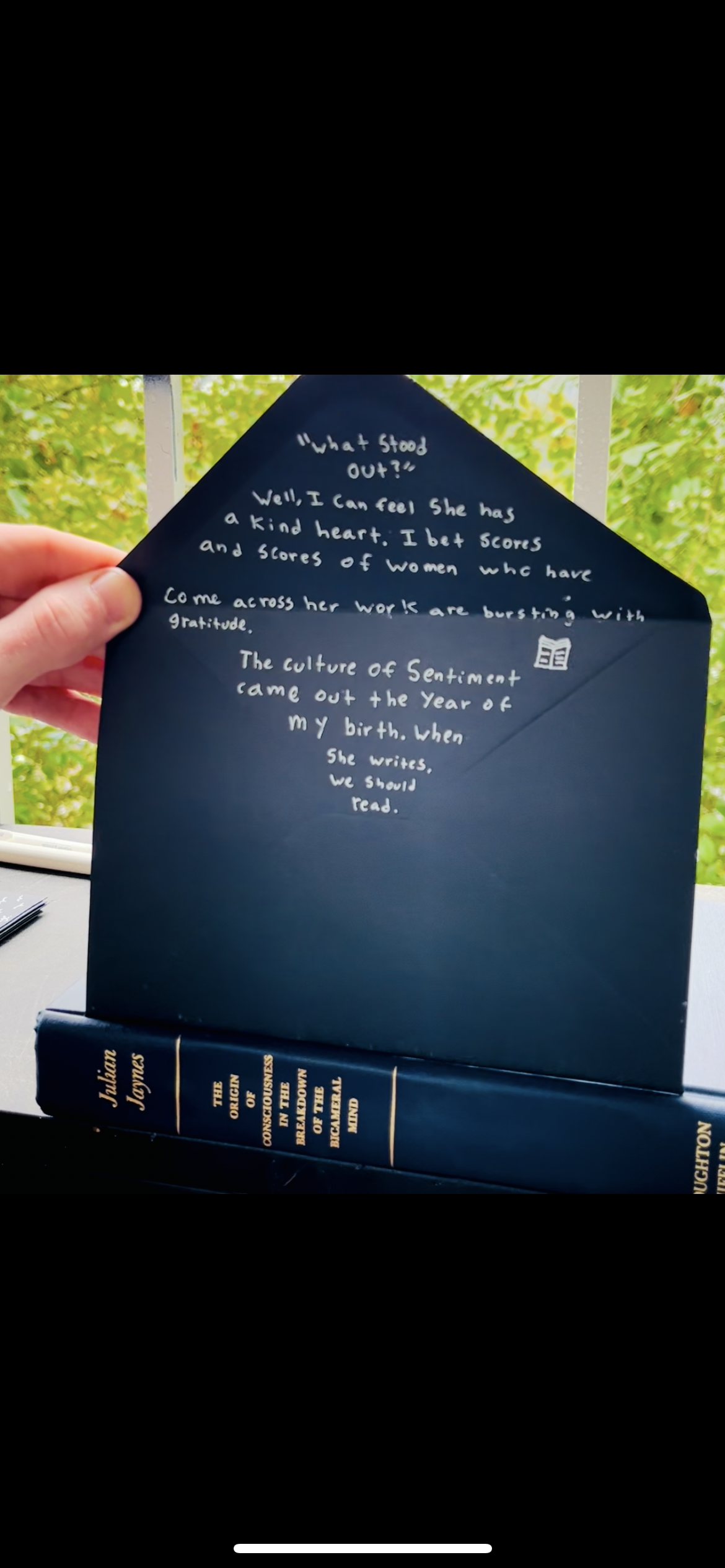 A handwritten note on a navy blue envelope with a book underneath. The note talks about a woman with a kind heart and her work in the culture of sentiment. The book is titled 'The Origin of Conscience in the Business of the Mind' by J. G. Bennett.