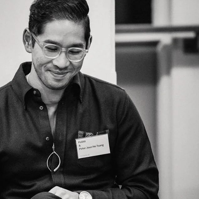 A man with glasses and dark hair, wearing a dark button-up shirt, smiling and looking down. He has a name tag that reads 'Pollitt' and 'Peter Jeun Ho Tsaung' on his shirt.