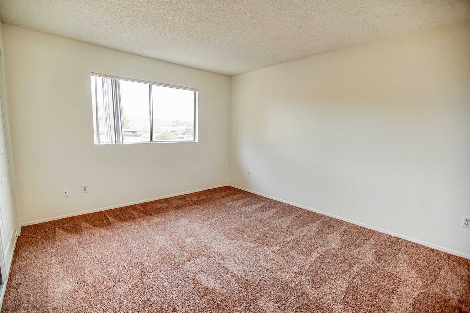This image includes a look into a bedroom with carpeted flooring and a large window.