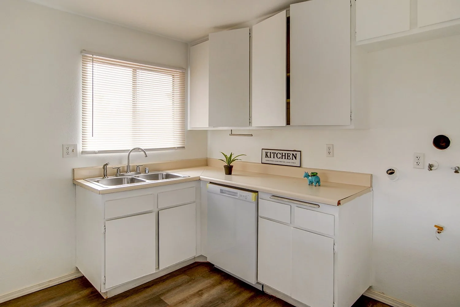 This image showcases the kitchen with white cabinets and a white sink. 