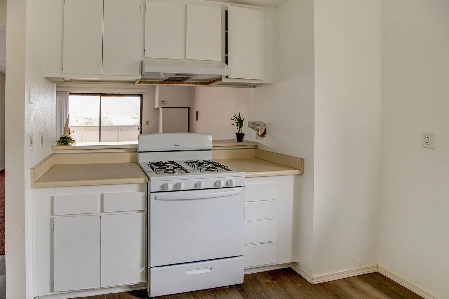 This image shows the kitchen featuring white cabinets and a white stove.